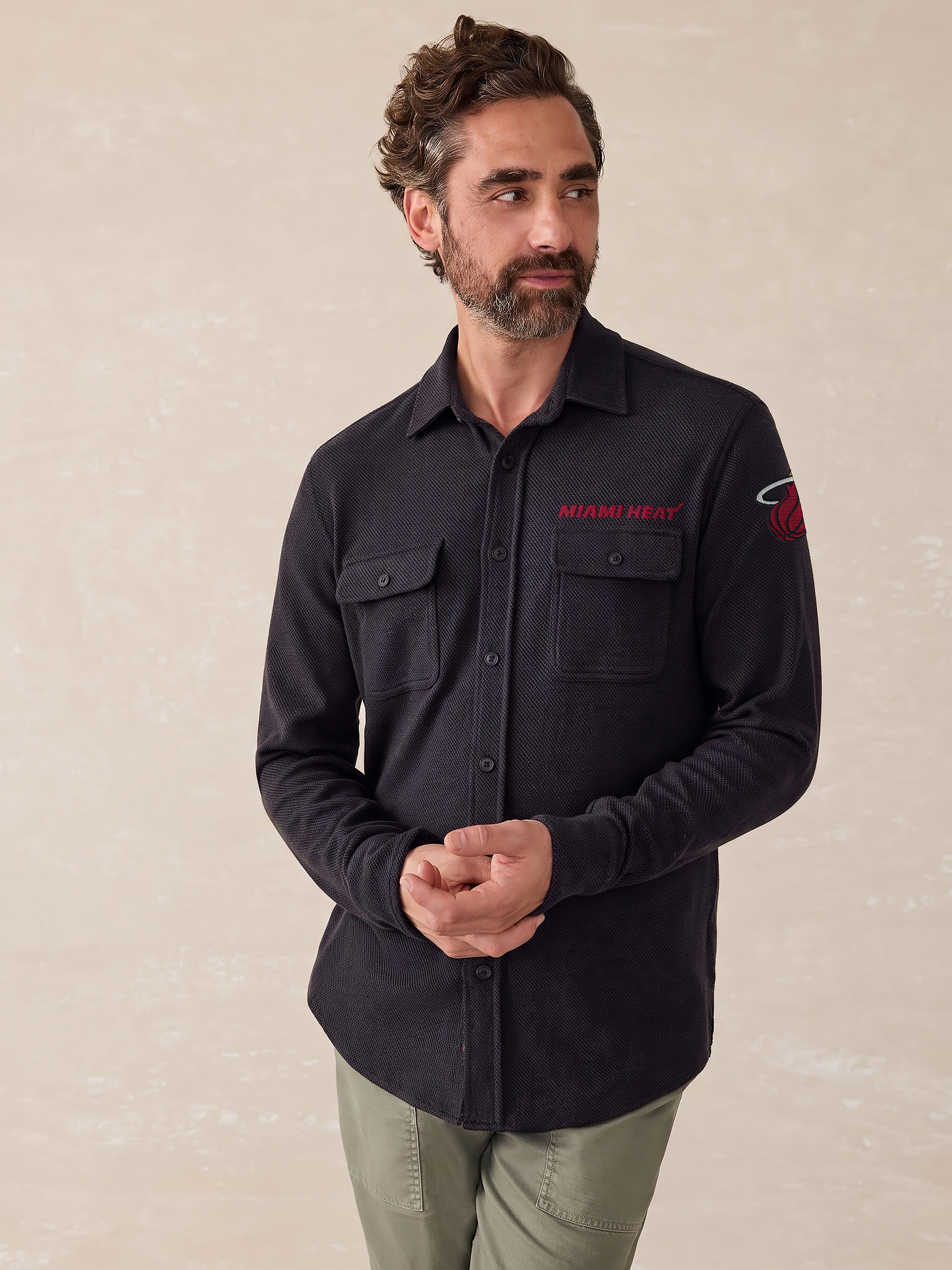 A man wearing a black Miami Heat button down shirt