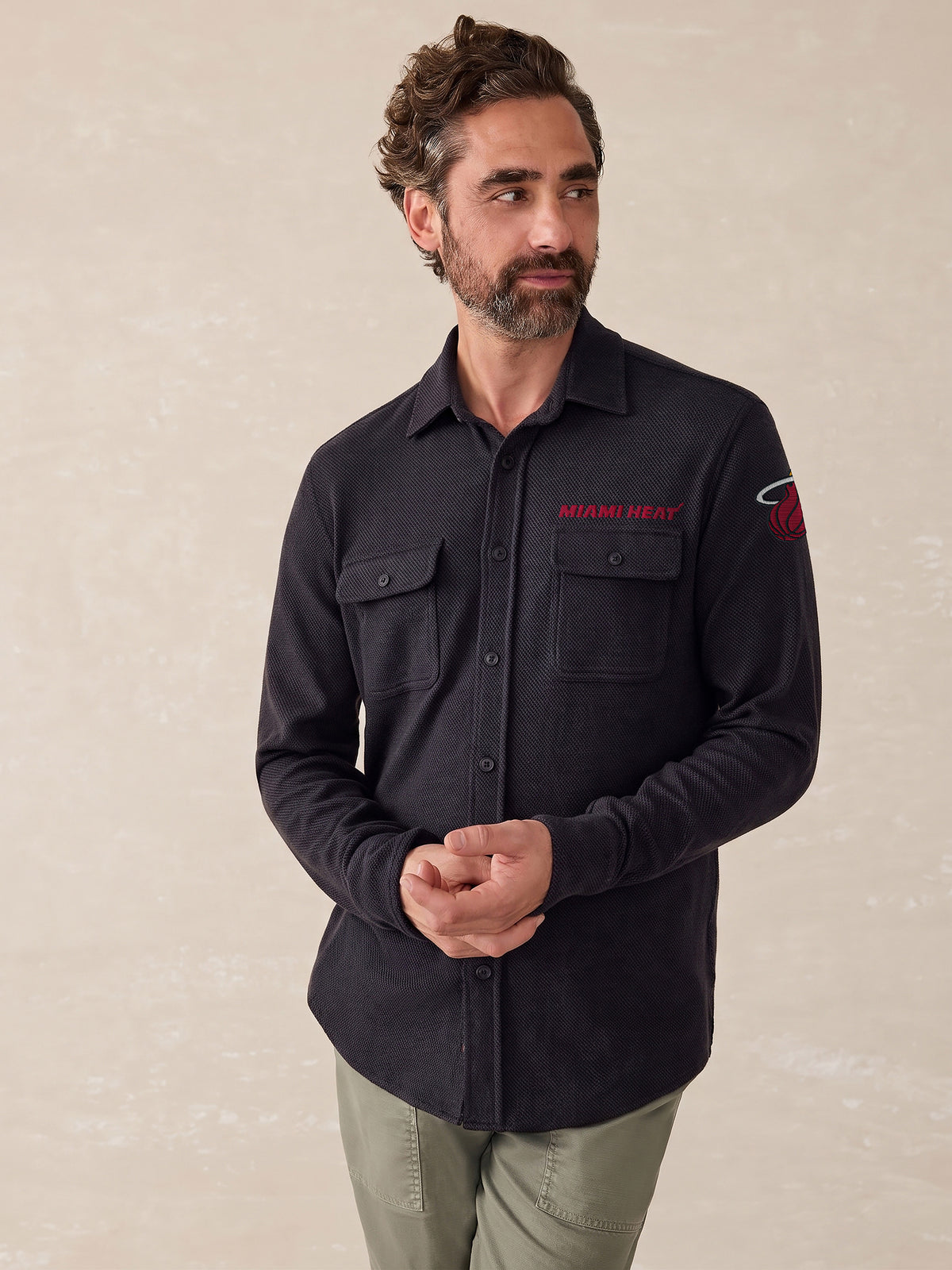 A man wearing a black Miami Heat button down shirt, image 1 of 2