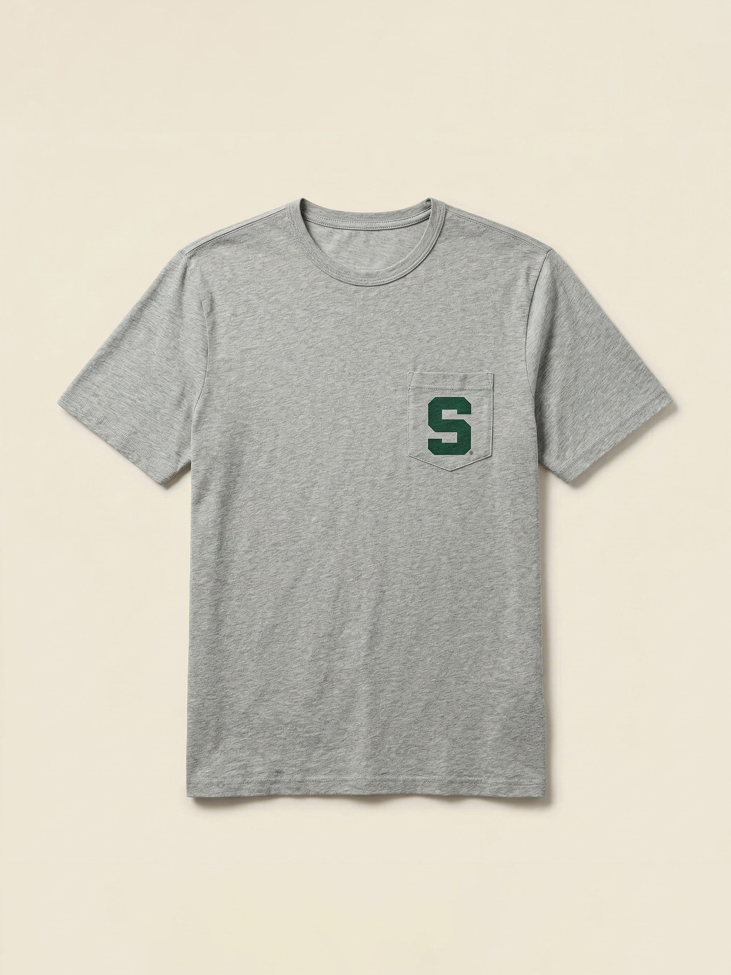 Grey t-shirt with a Michigan State graphic on the left chest pocket against a beige background