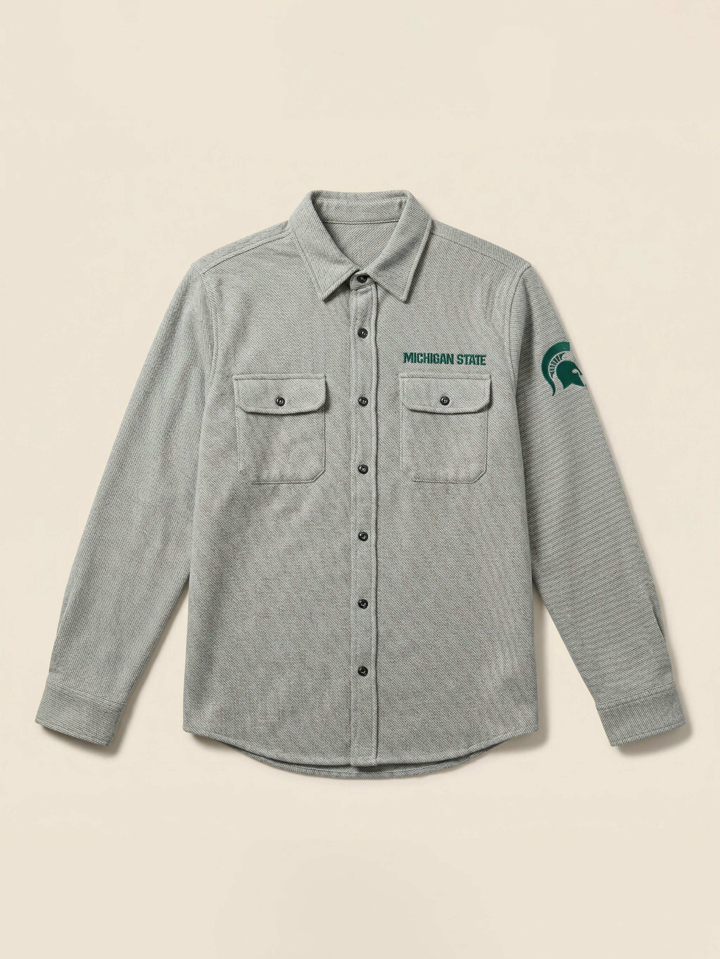 Gray flannel shirt with Michigan State logo on the left chest and arm against a beige background