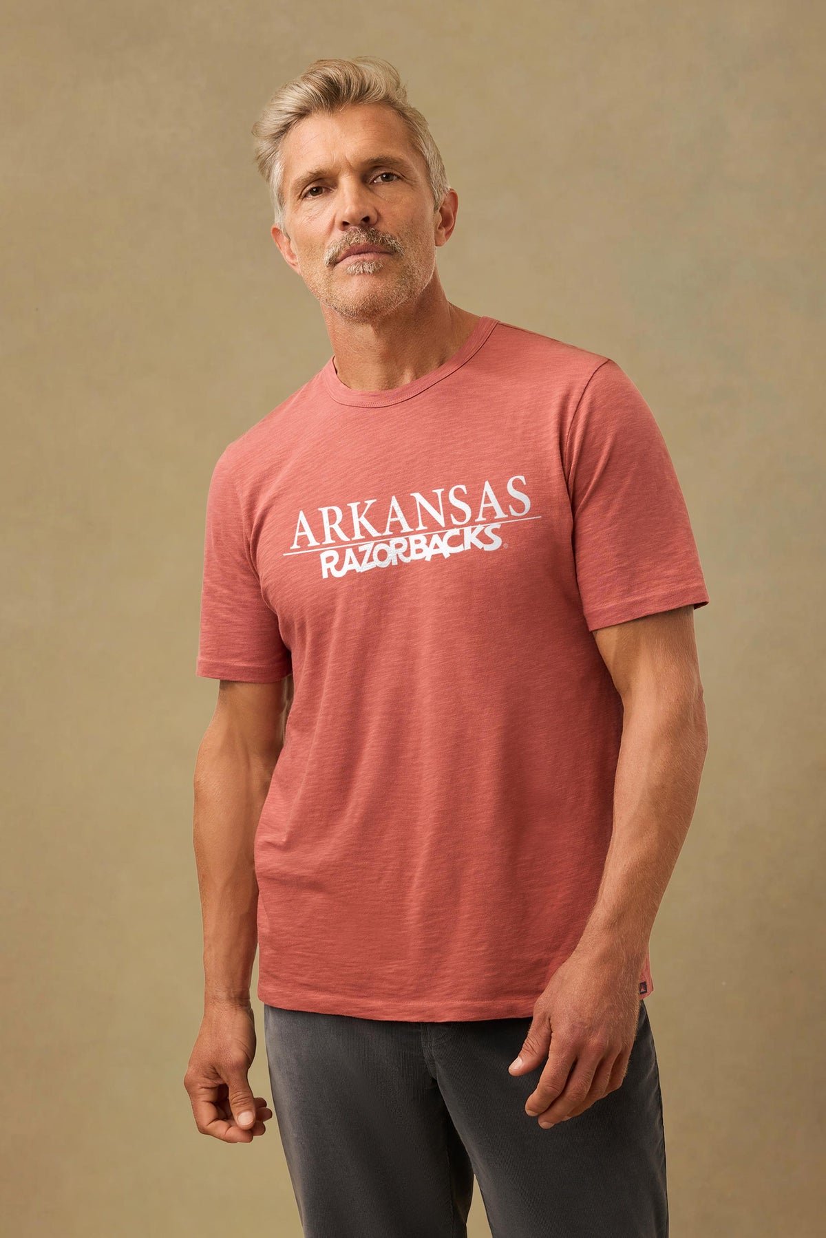 A man wearing a red University of Arkansas tee and black pants, image 1 of 1