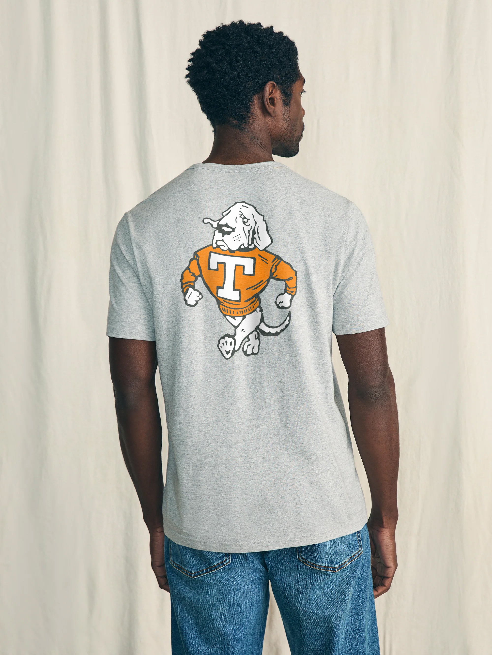 Person wearing a gray t-shirt with a University of Tennessee graphic on the back against a plain background