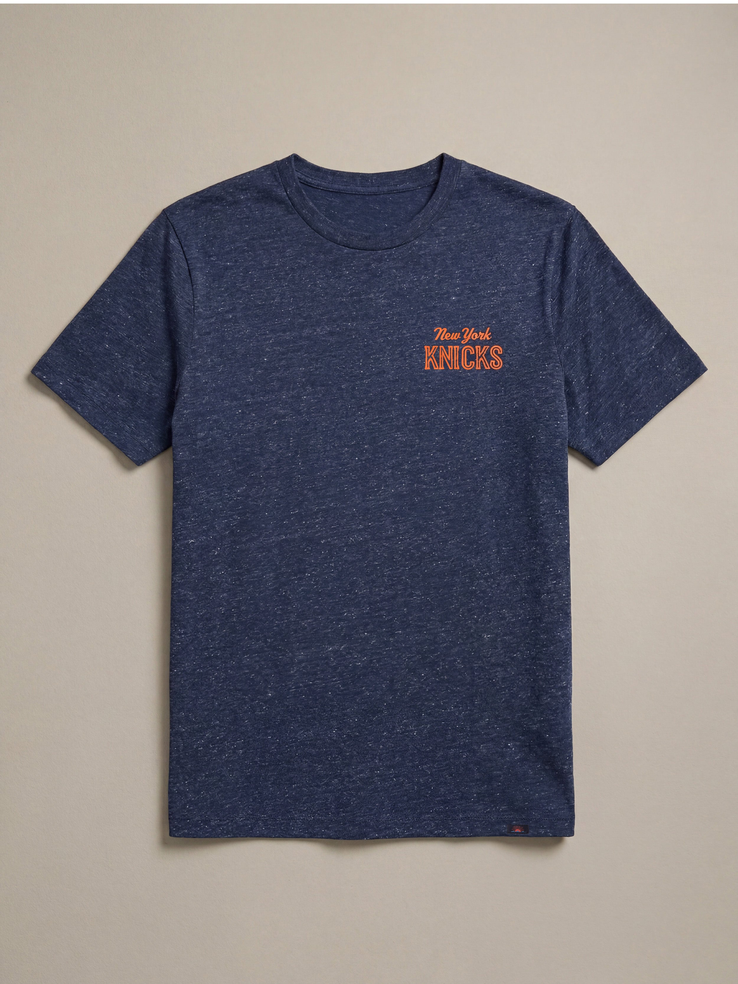 Blue t-shirt with 'New York Knicks' logo on a beige background