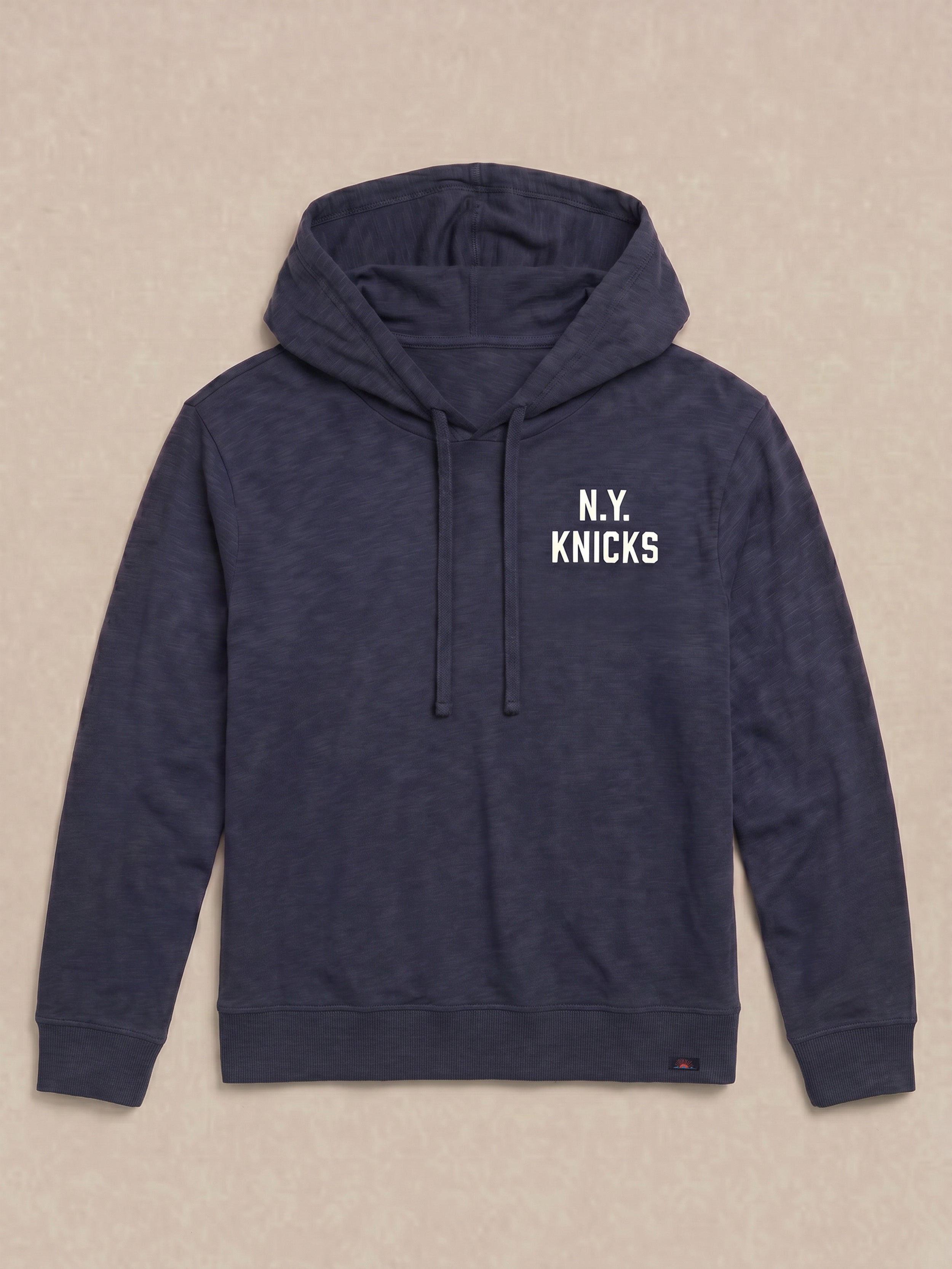 Navy blue hoodie with 'N.Y. Knicks' graphic text on the front left chest against a beige background