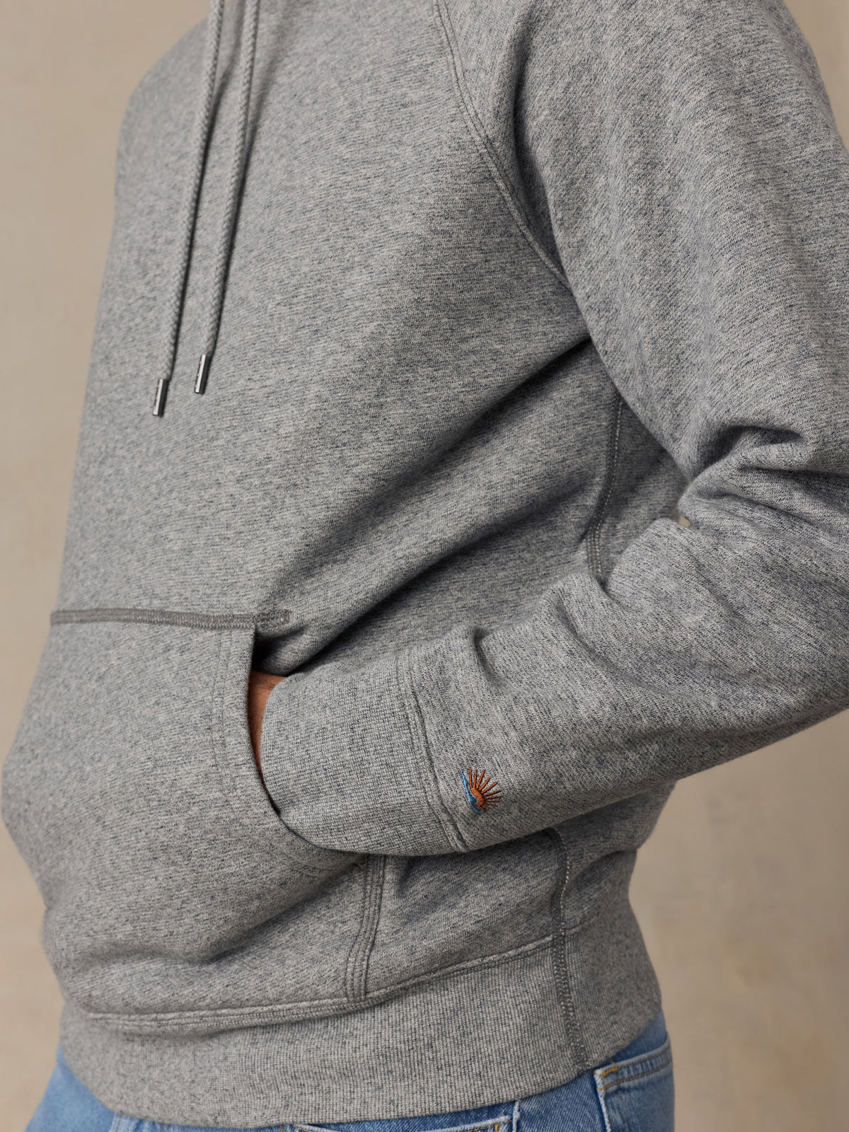 Close up of a man wearing a grey hoodie and blue jeans, image 5 of 7