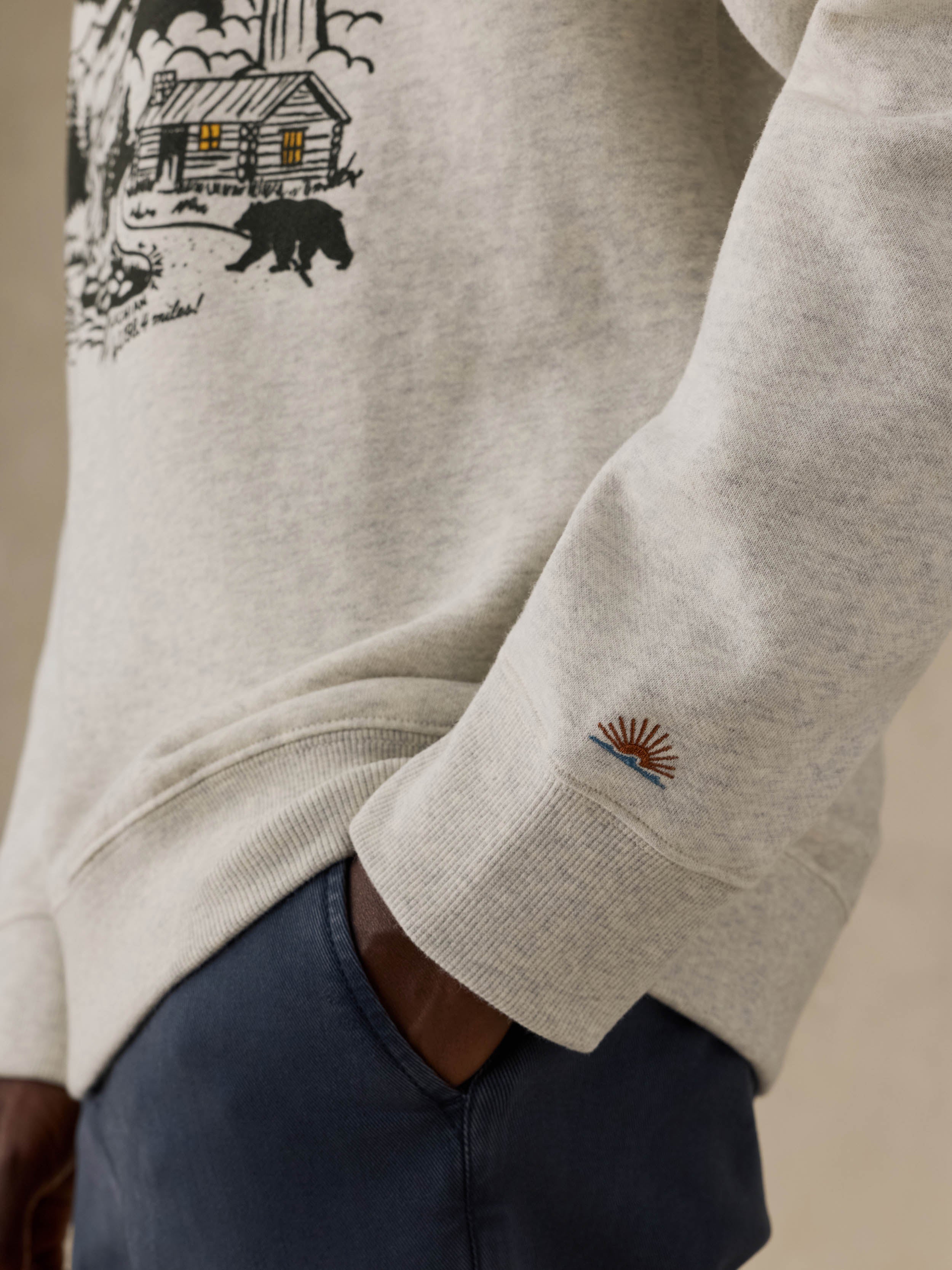 Man wearing a gray sweatshirt with a nature graphic and text on a beige background