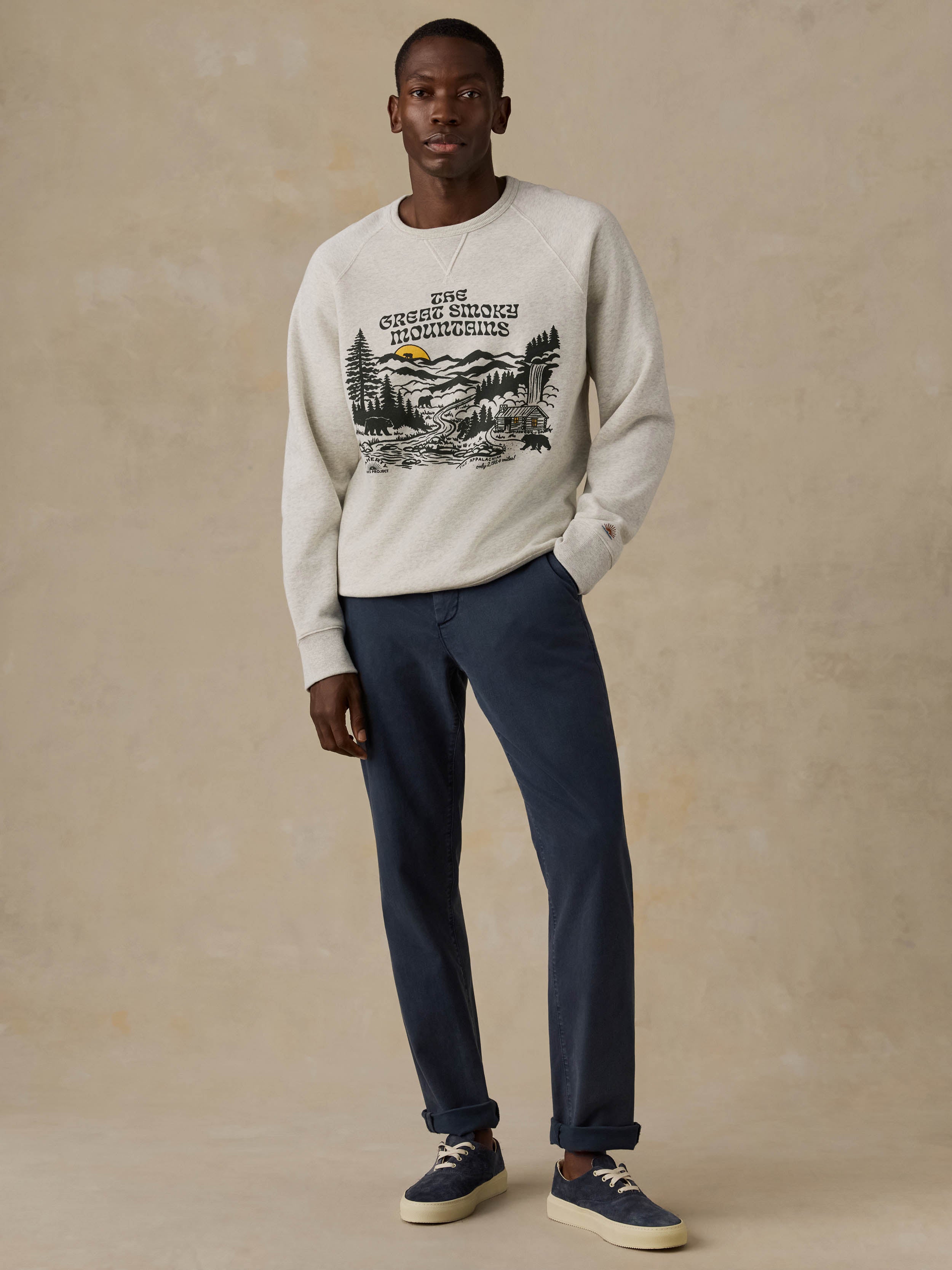 Man wearing a gray sweatshirt with a nature graphic and text on a beige background