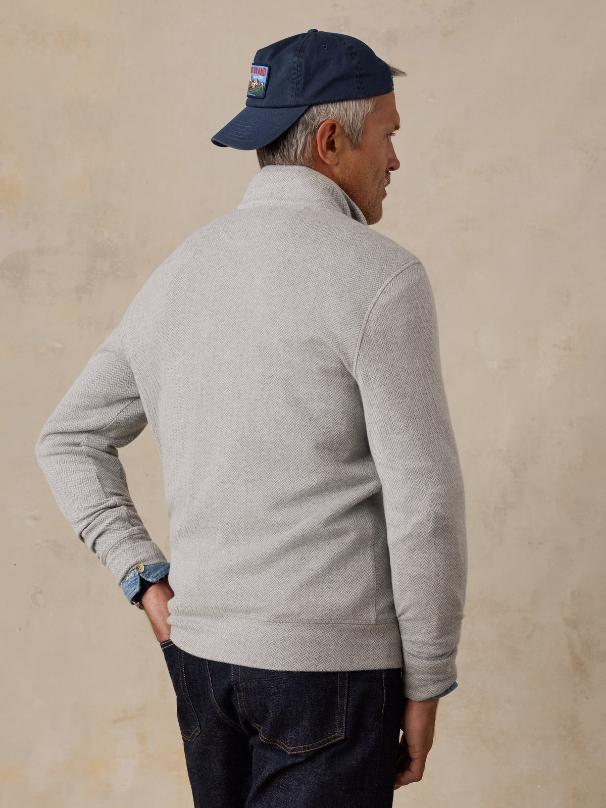 A man viewed from behind wearing a grey quarter zip and jeans, image 4 of 6