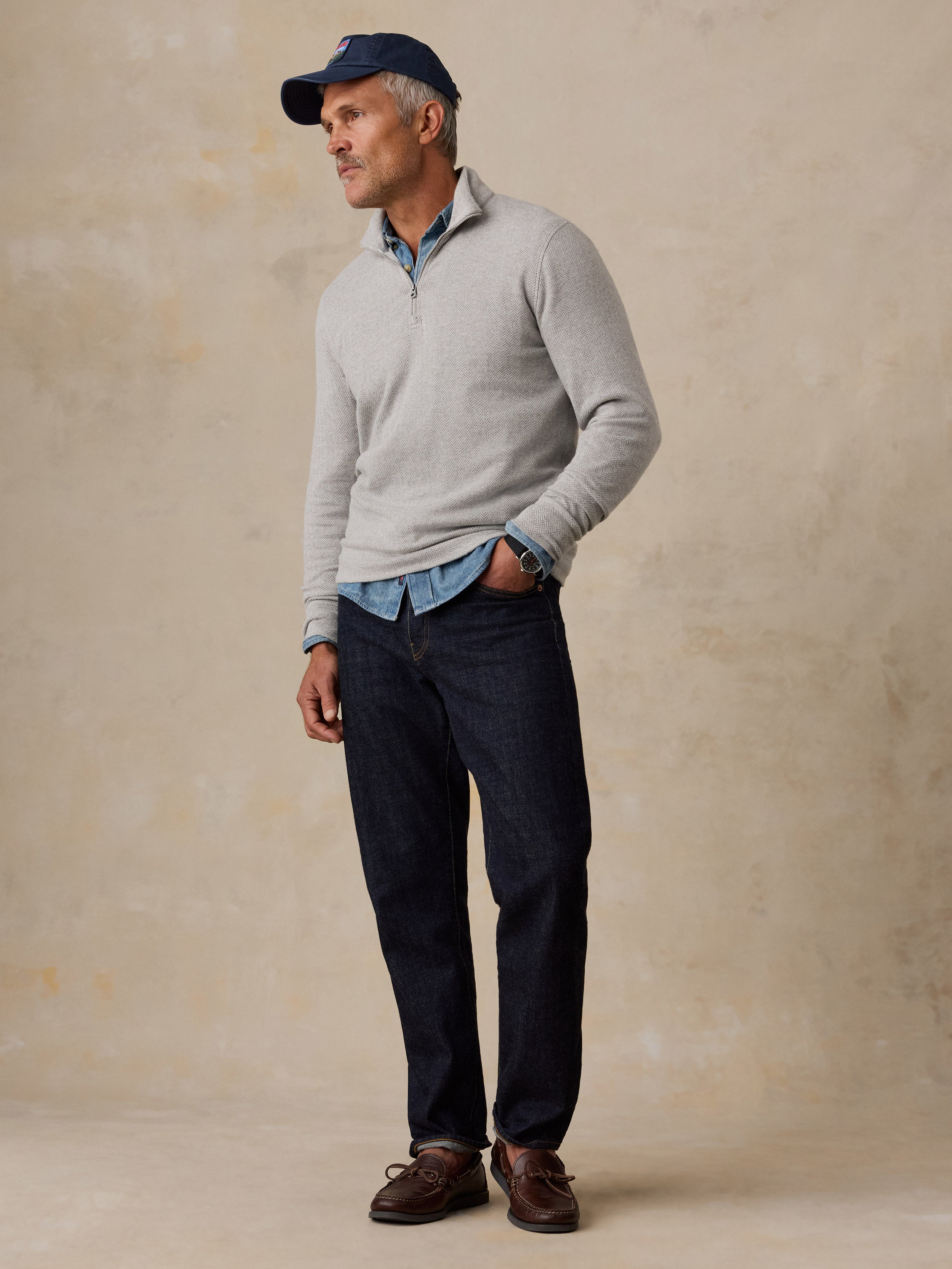 A man wearing a grey quarter zip and jeans