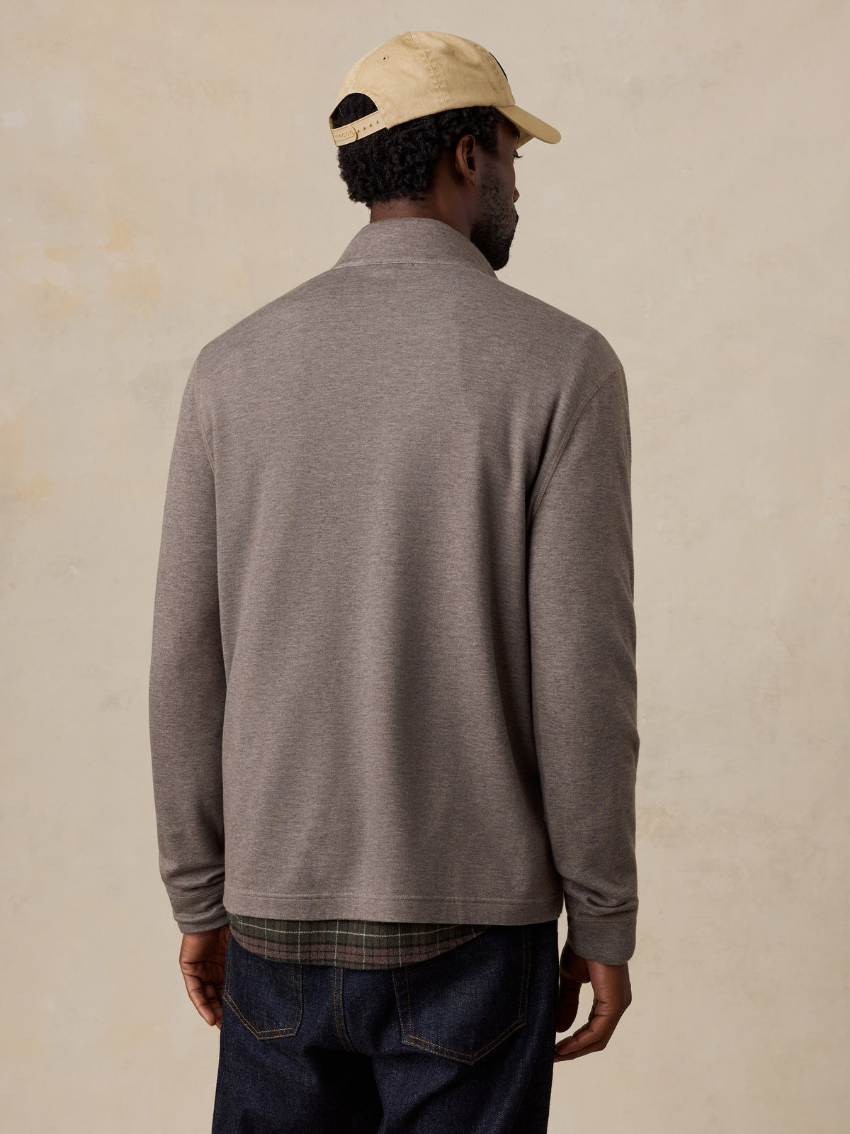 A man viewed from behind wearing a light brown quarter zip, image 2 of 5