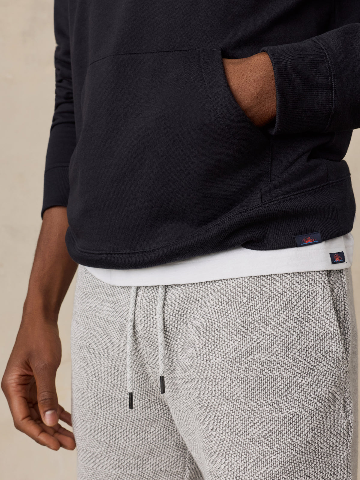 Close up of a man wearing a black hoodie and lounge shorts, image 6 of 6