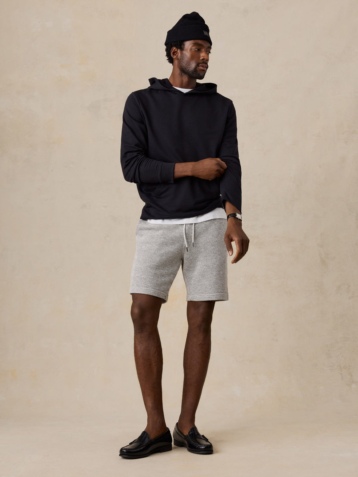 A man wearing a black hoodie and lounge shorts, image 2 of 6