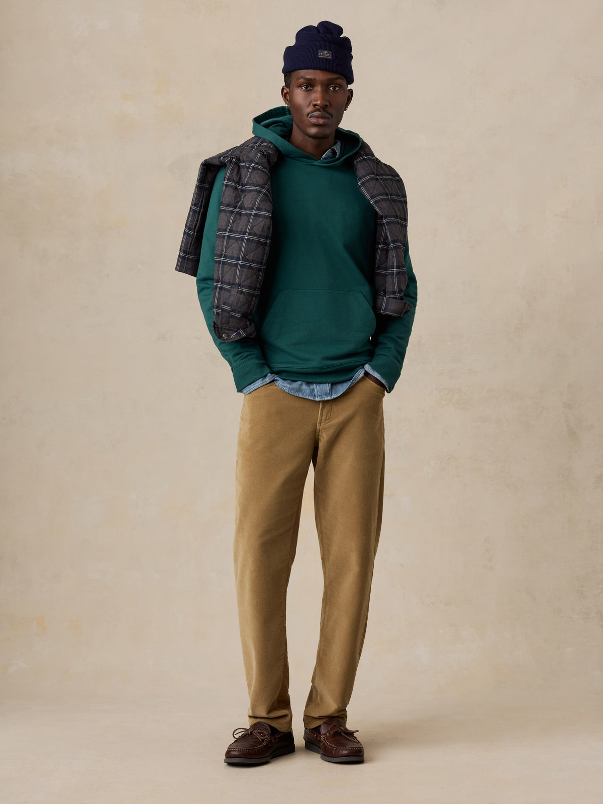 A man wearing a teal hoodie and tan pants, image 2 of 6