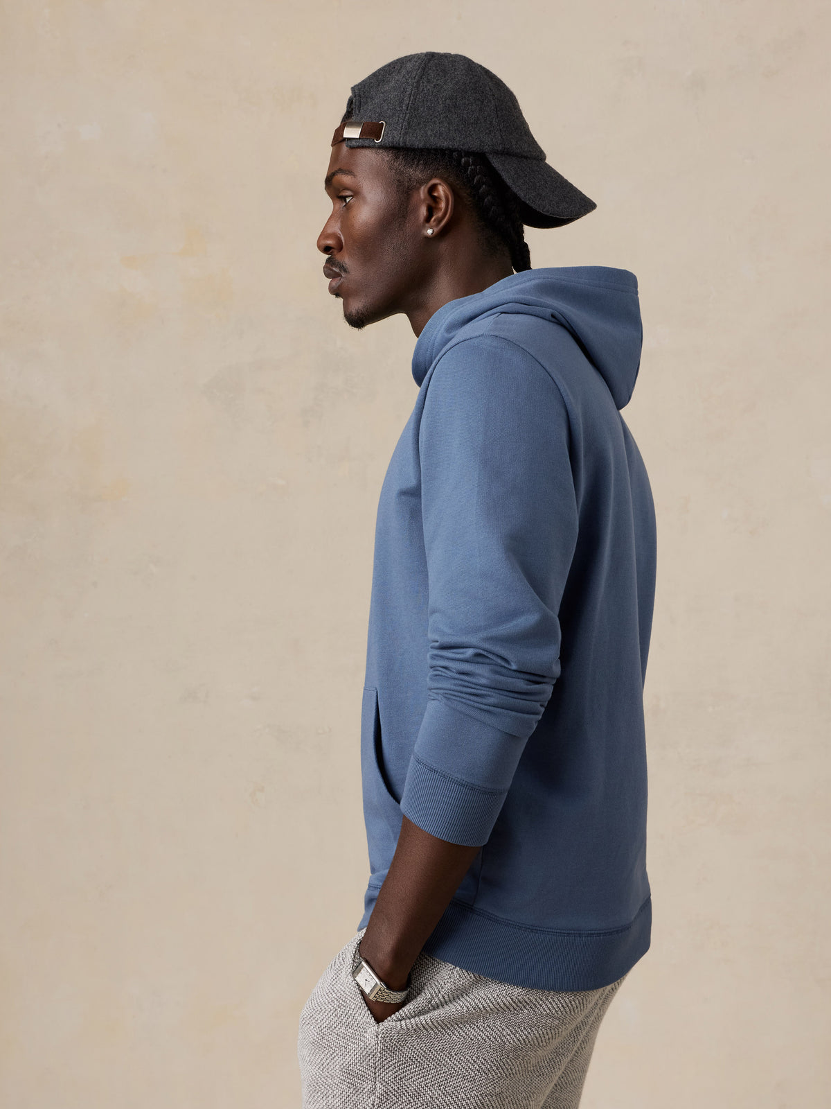 A man wearing a blue hoodie and grey hat, image 3 of 5