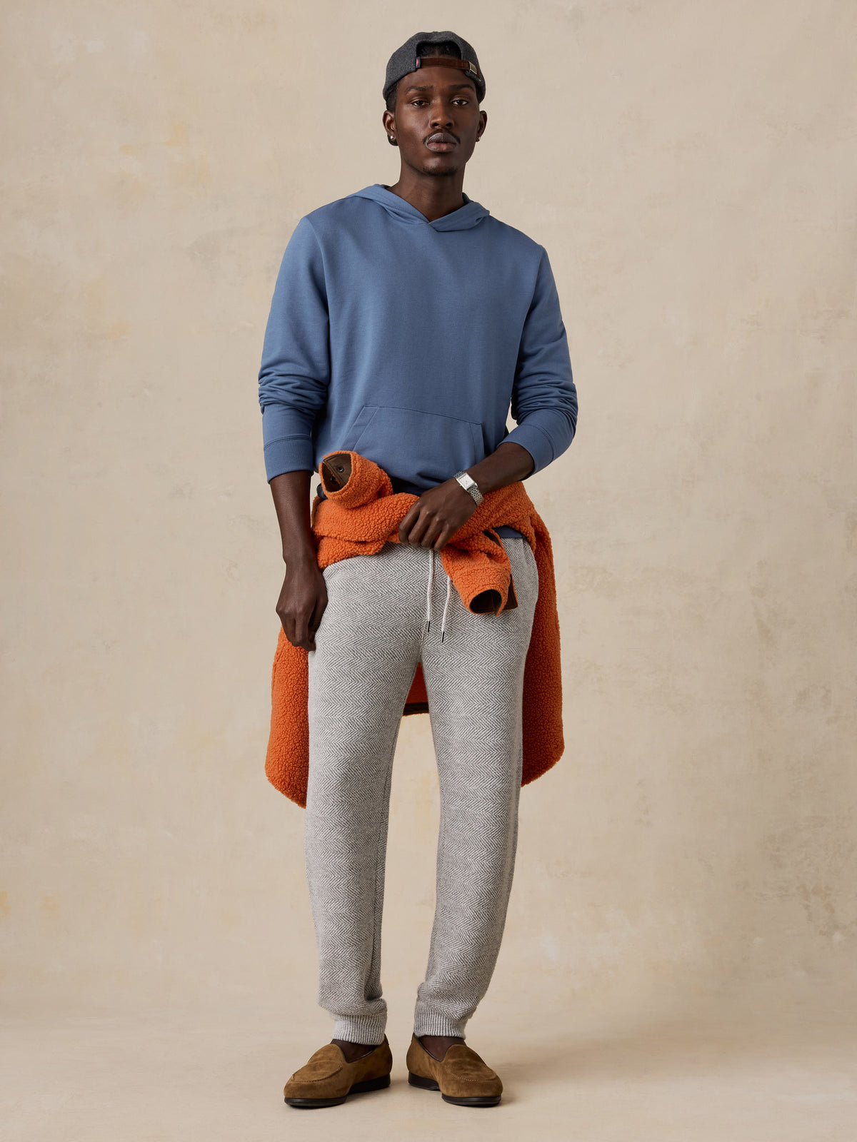 A man wearing a blue hoodie and sweatpants, image 1 of 5
