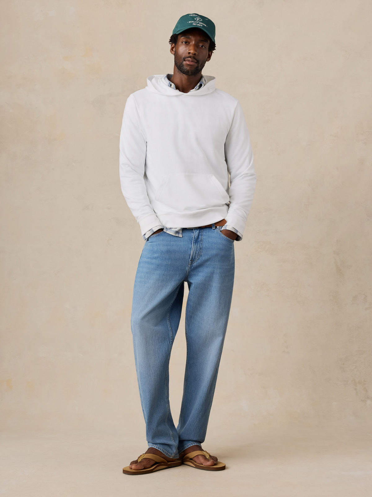 A man wearing a white hoodie and jeans, image 2 of 6