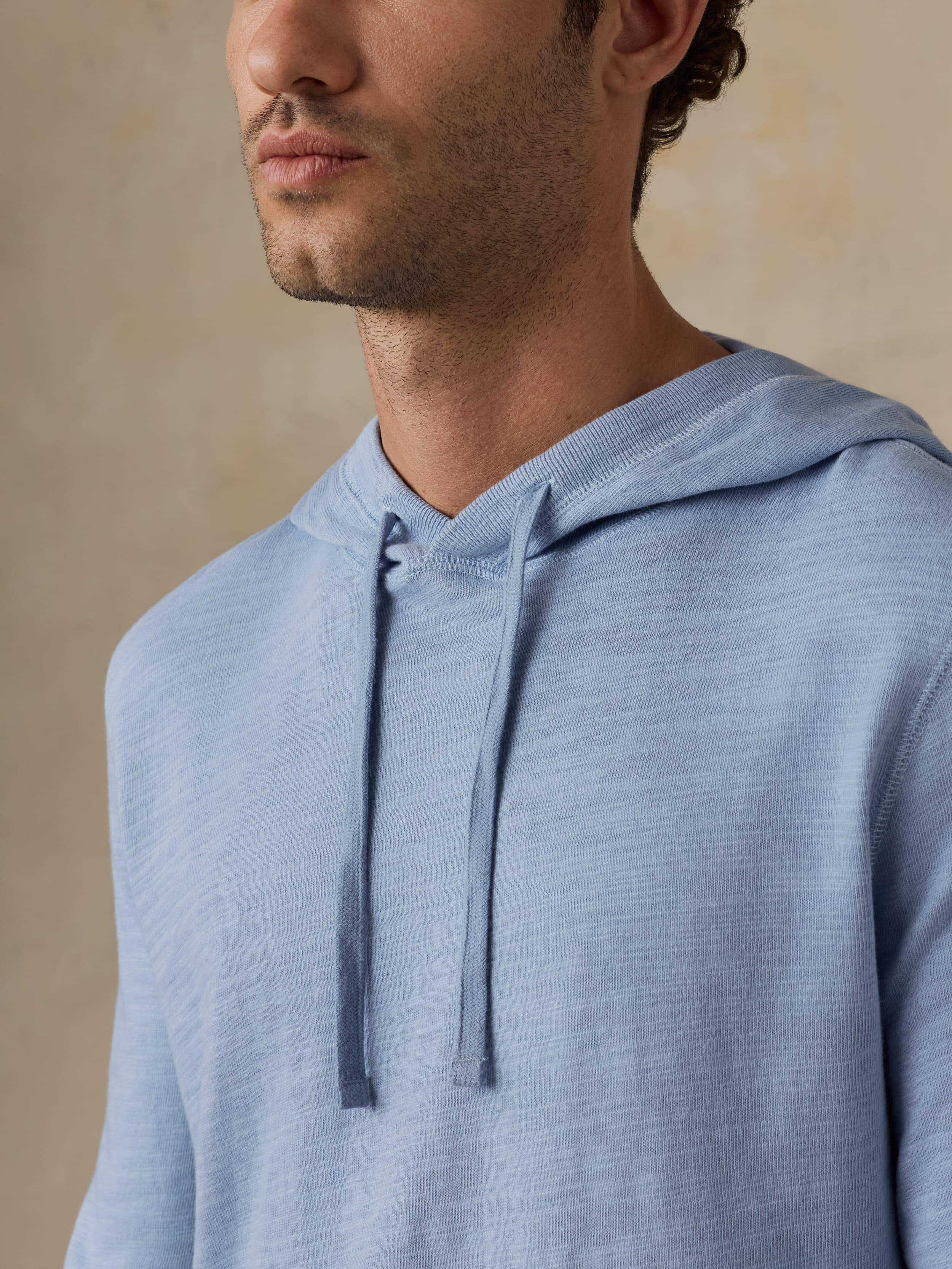 Man wearing a blue hoodie against a beige background
