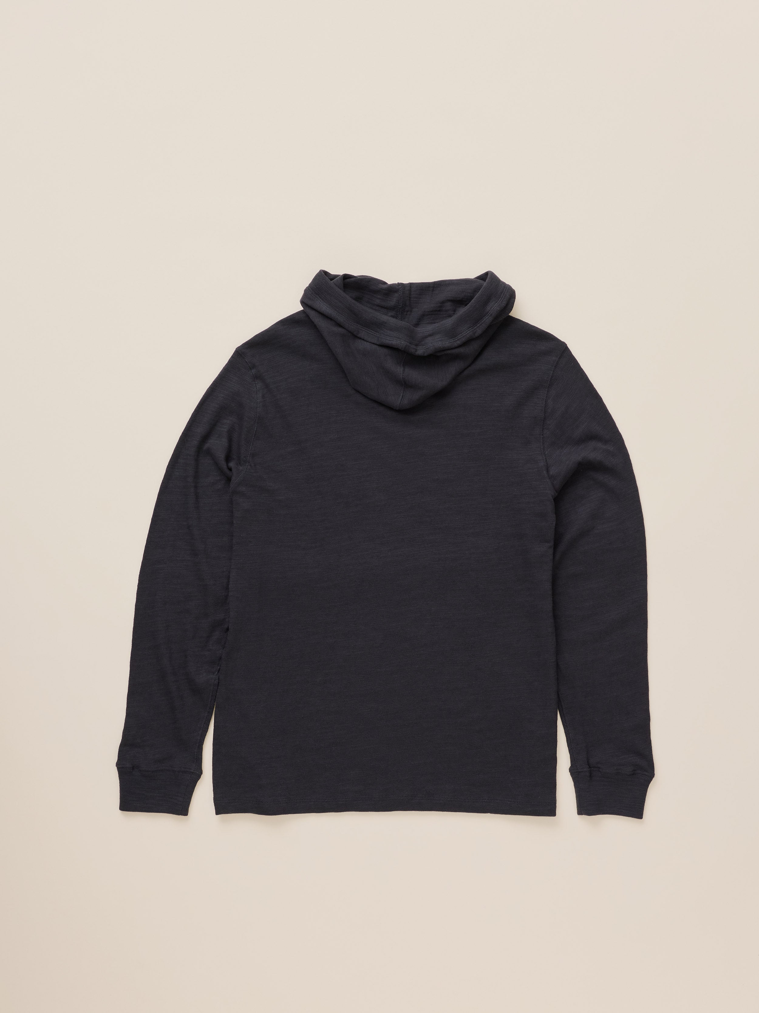 A black hooded long-sleeve top, shown from the back, laid flat against a light beige background.