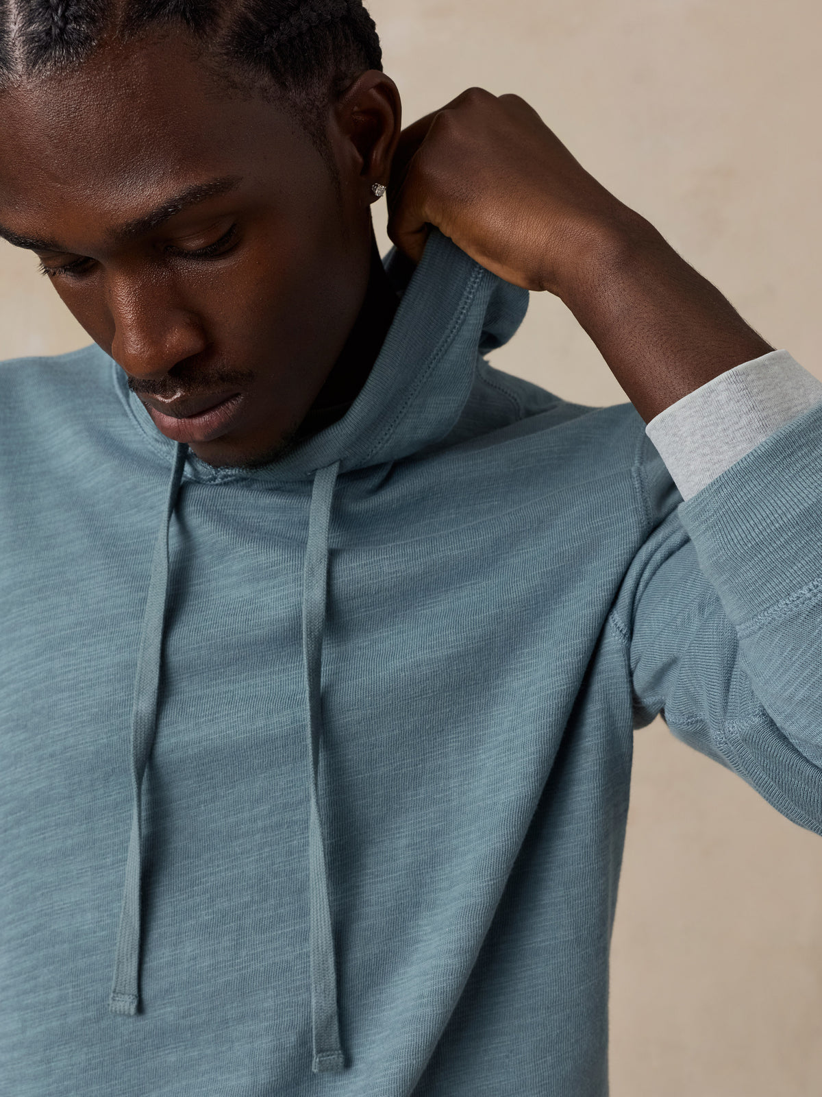 A close-up of a man wearing a slate blue-gray hoodie.