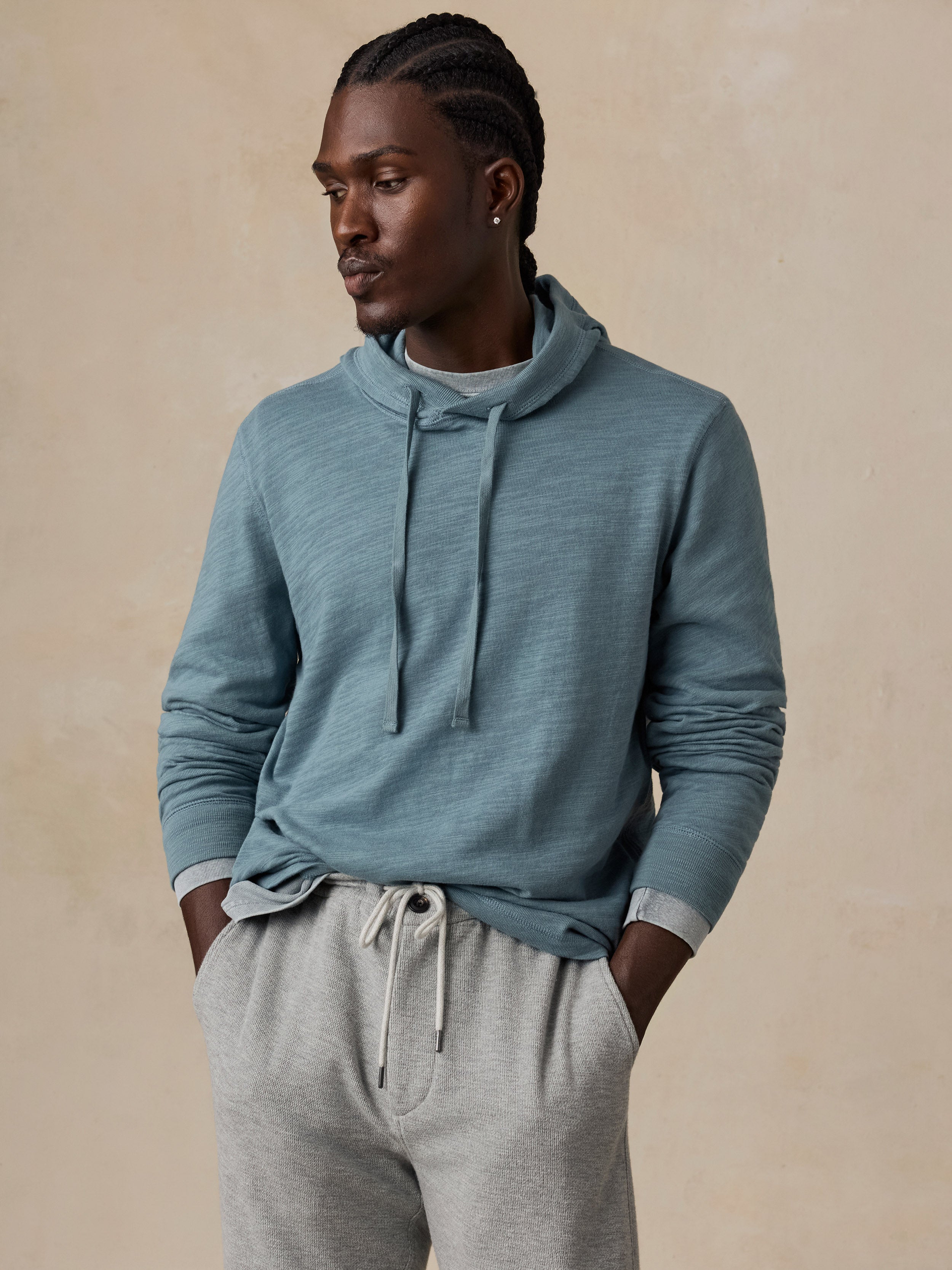 A man wearing a slate blue textured knit hoodie and light gray sweatpants.