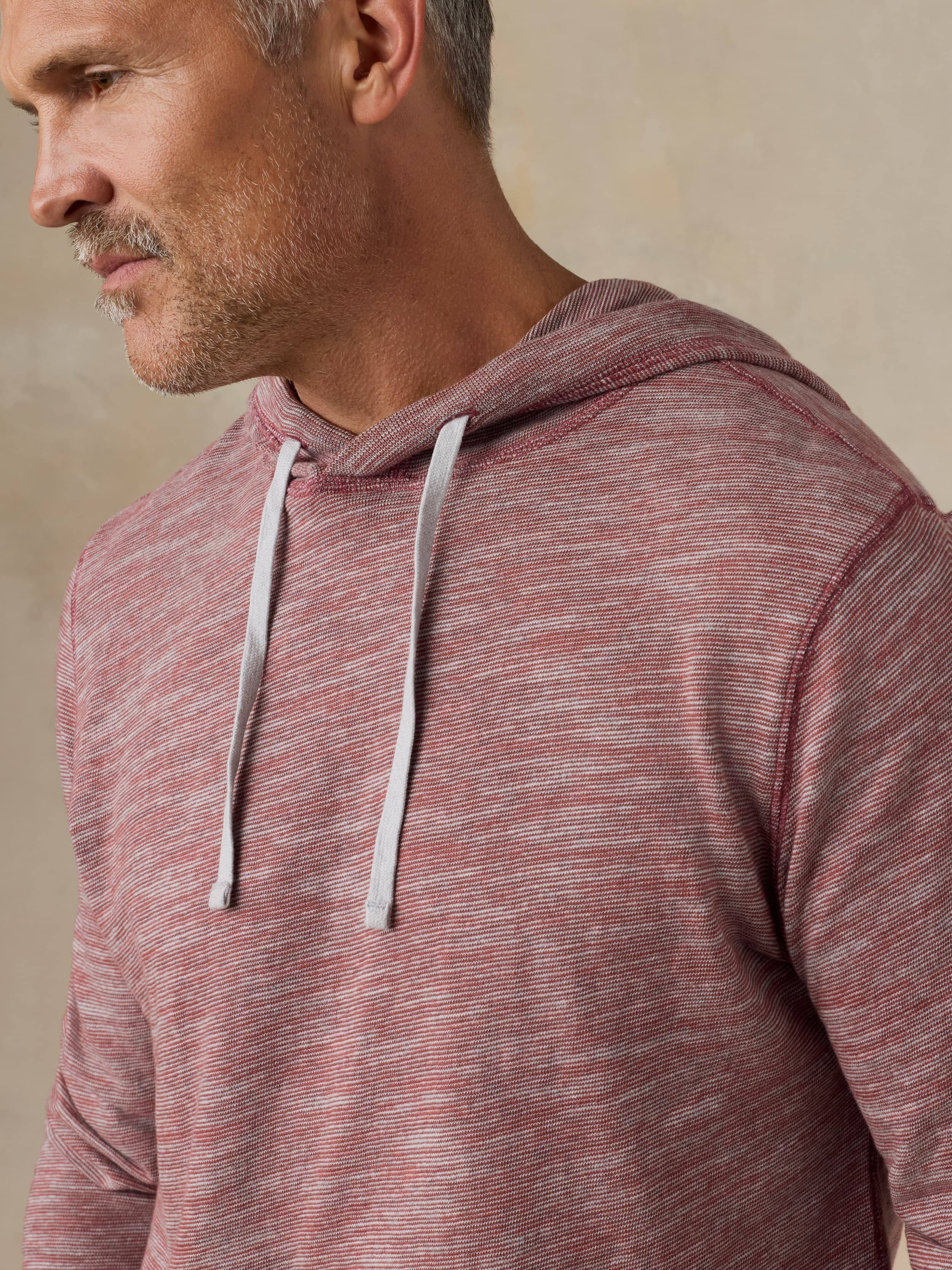 Man wearing a red heathered hoodie against a beige background