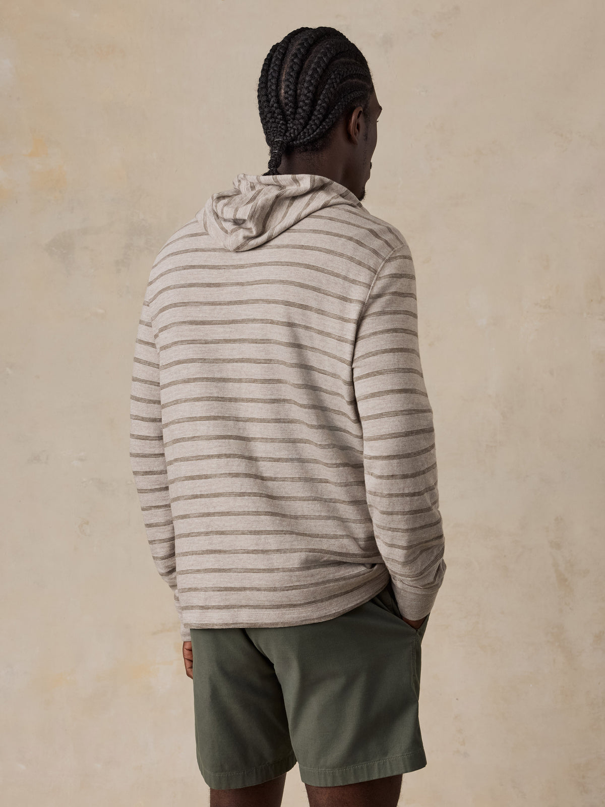 A man viewed from behind wearing a striped sweatshirt and green shorts, image 3 of 5