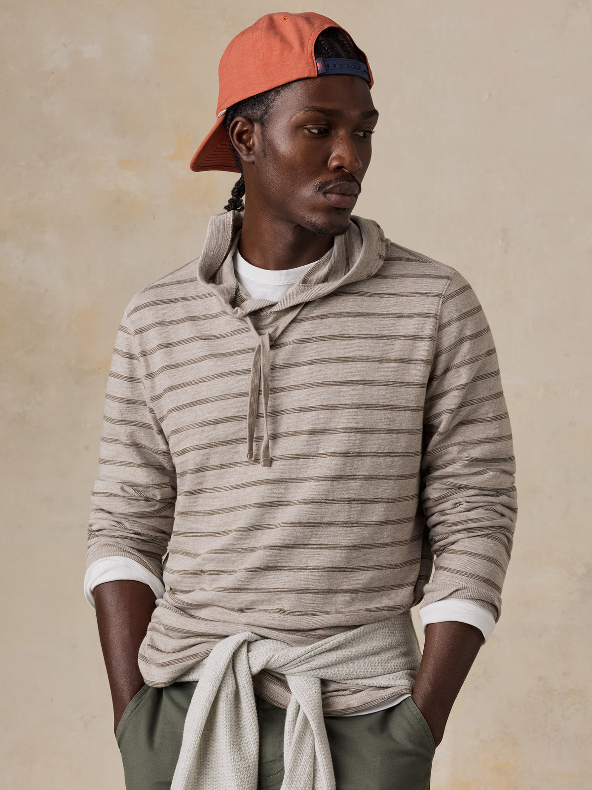A man wearing a striped sweatshirt and green shorts, image 4 of 5