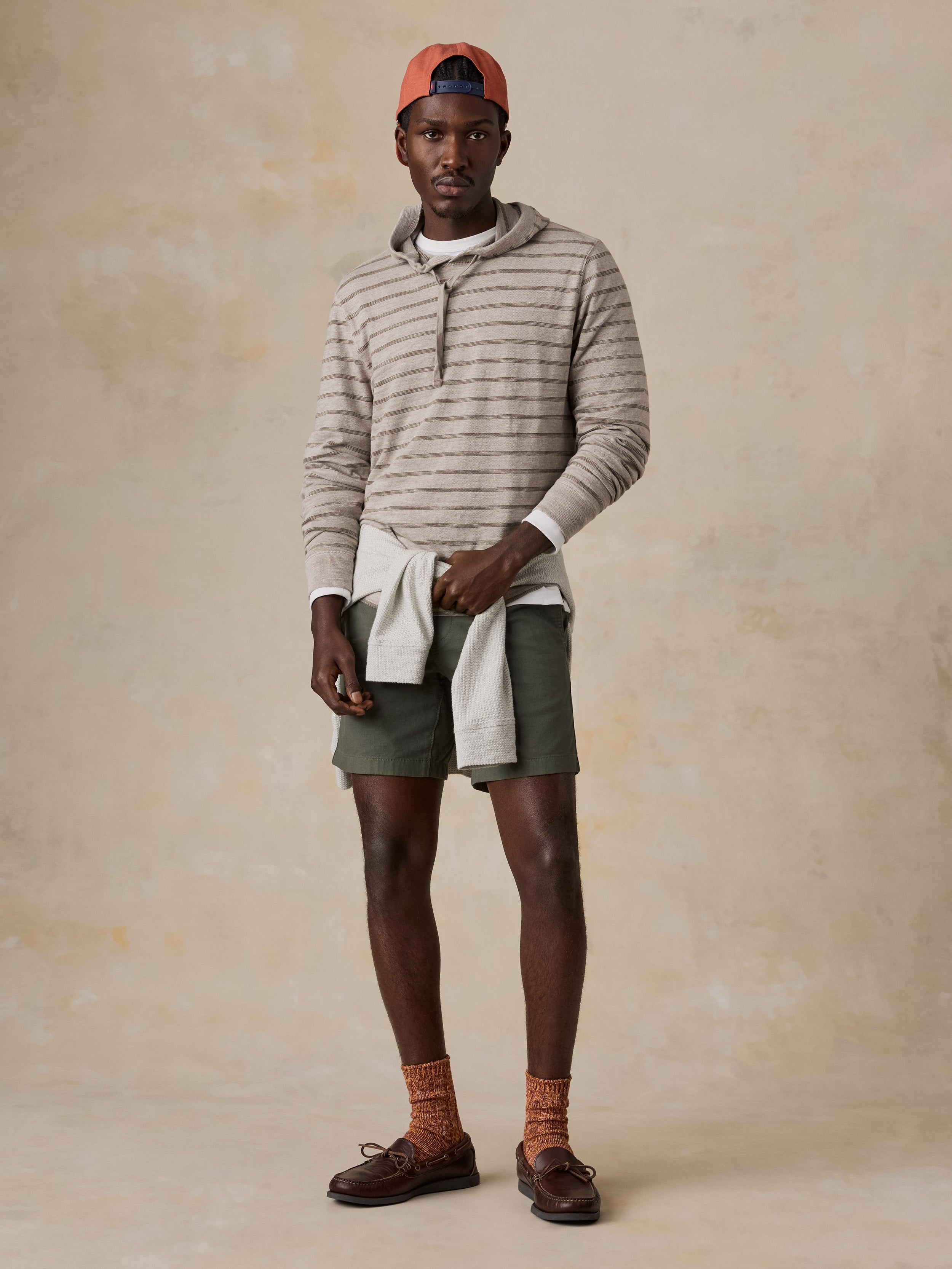A man wearing a striped sweatshirt and green shorts