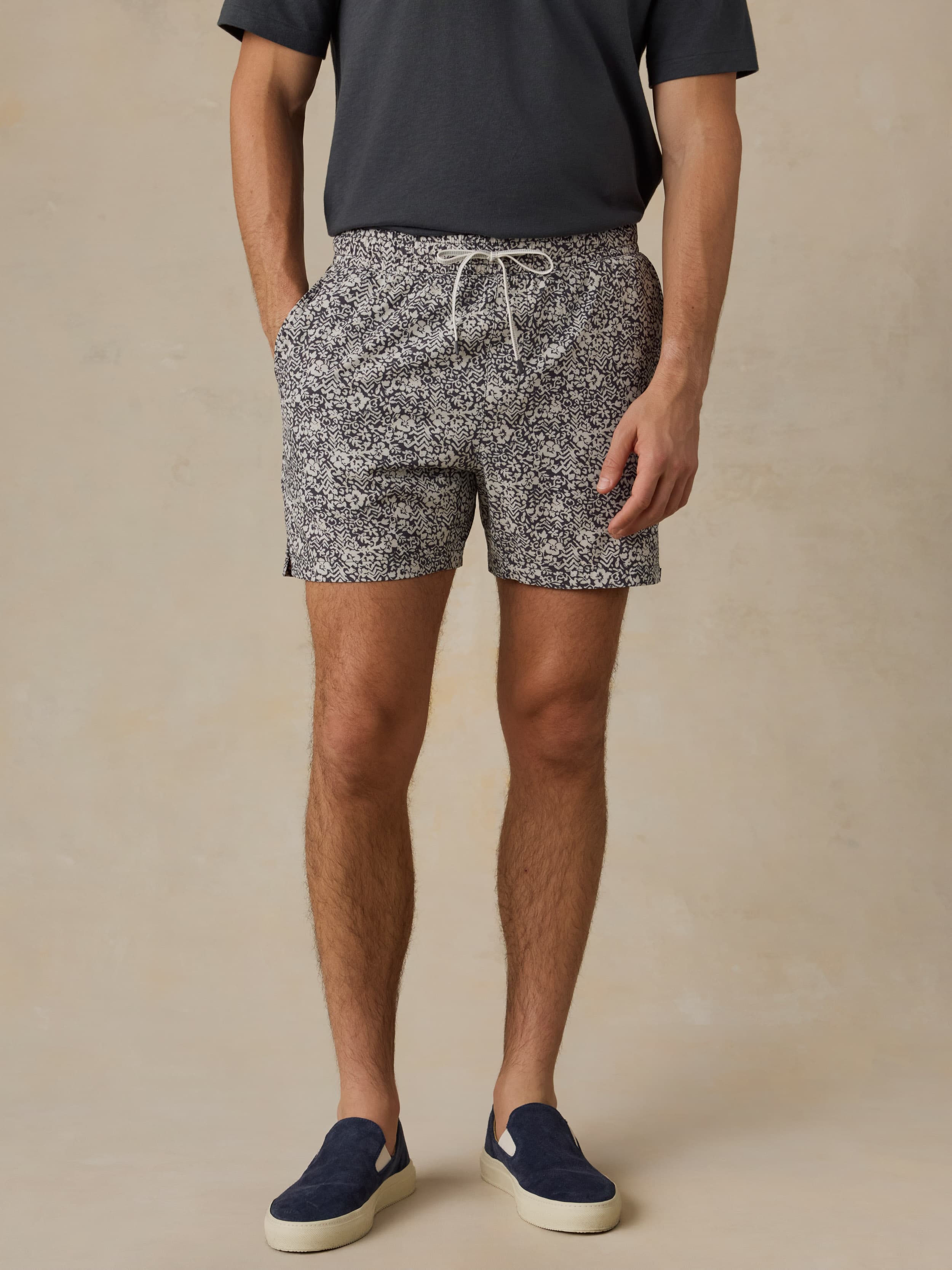 Man wearing patterned shorts and dark shoes on a beige background