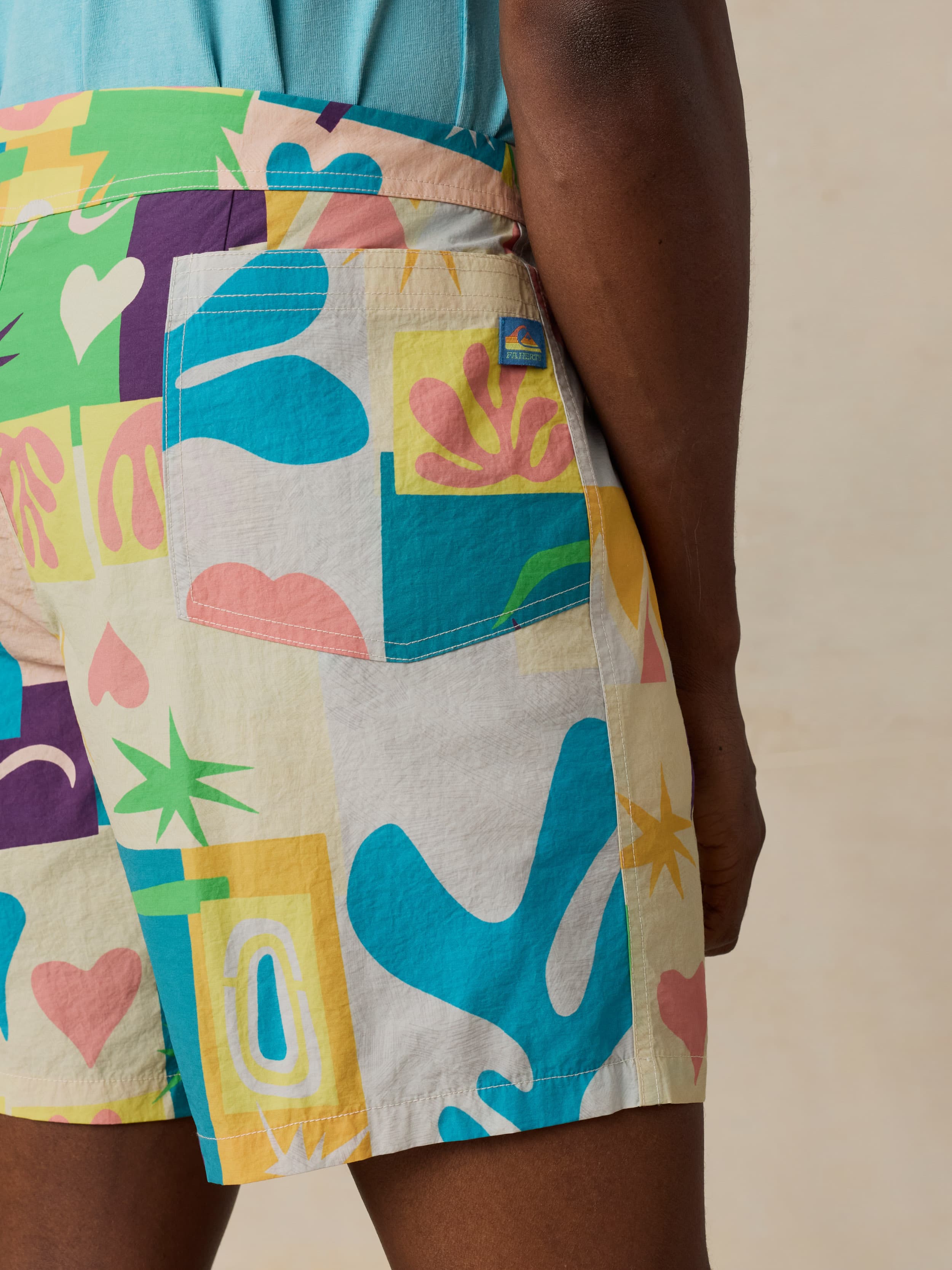 Colorful patterned swim shorts with abstract designs on a neutral background