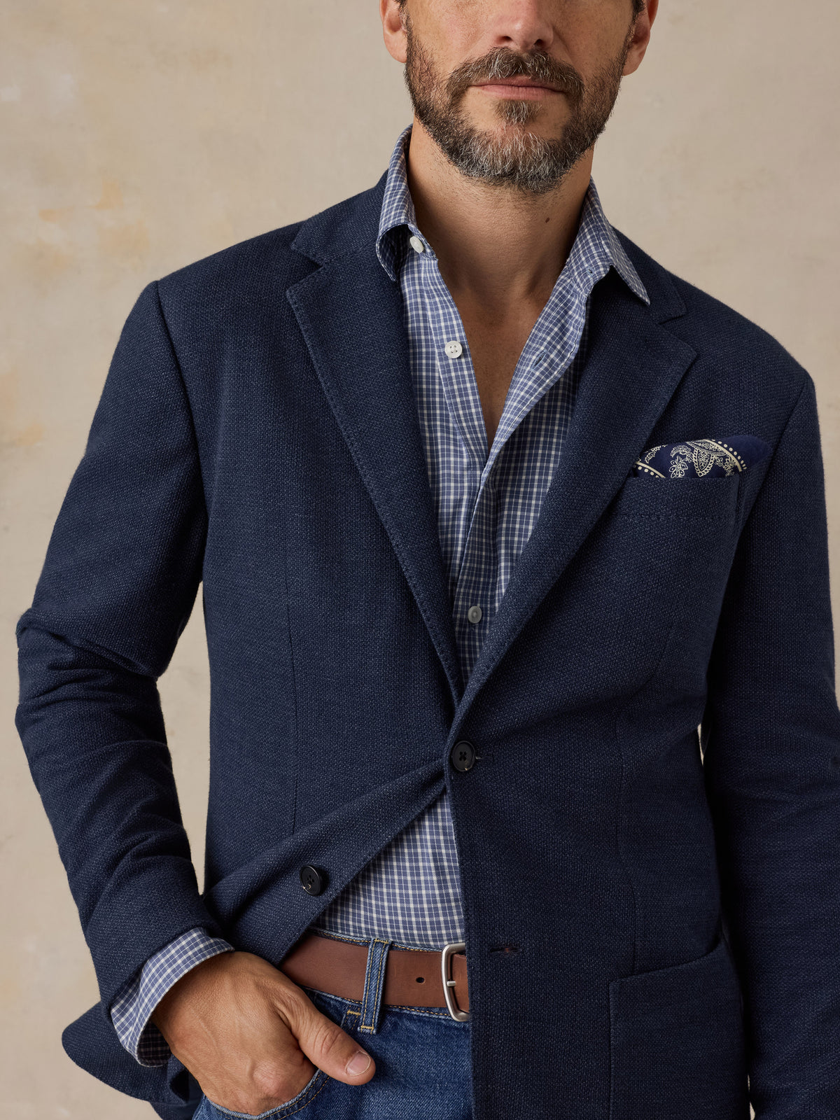 Man wearing a navy blazer over a blue button up shirt and blue jeans, image 3 of 5