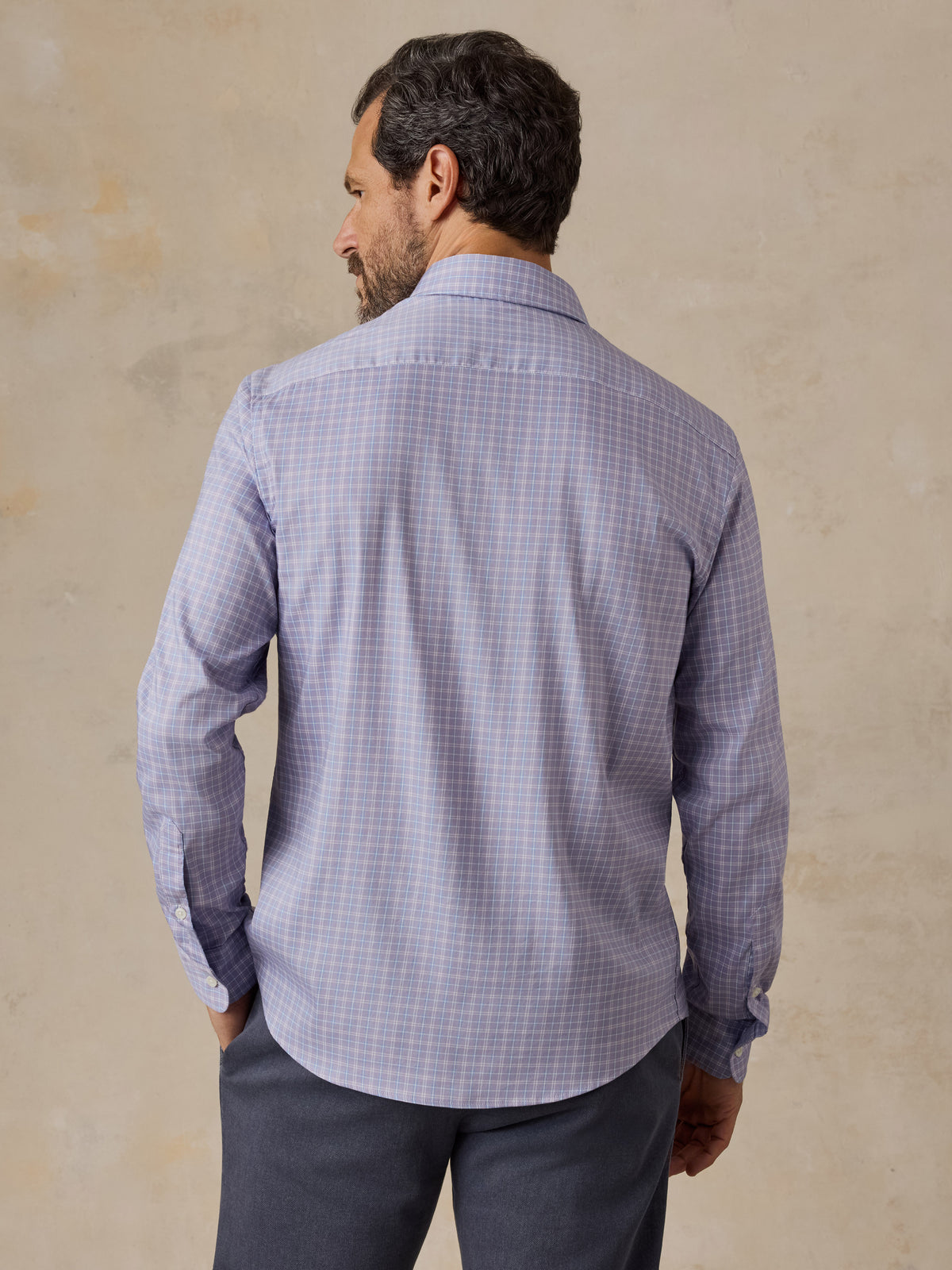 Man viewed from the back wearing a light purple plaid shirt and chino pants, image 3 of 5