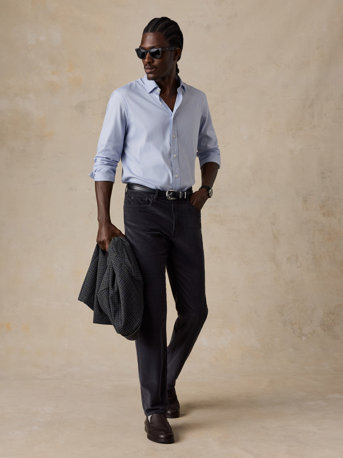 A man wearing a blue shirt, dark pants, and leather shoes, image 5 of 5