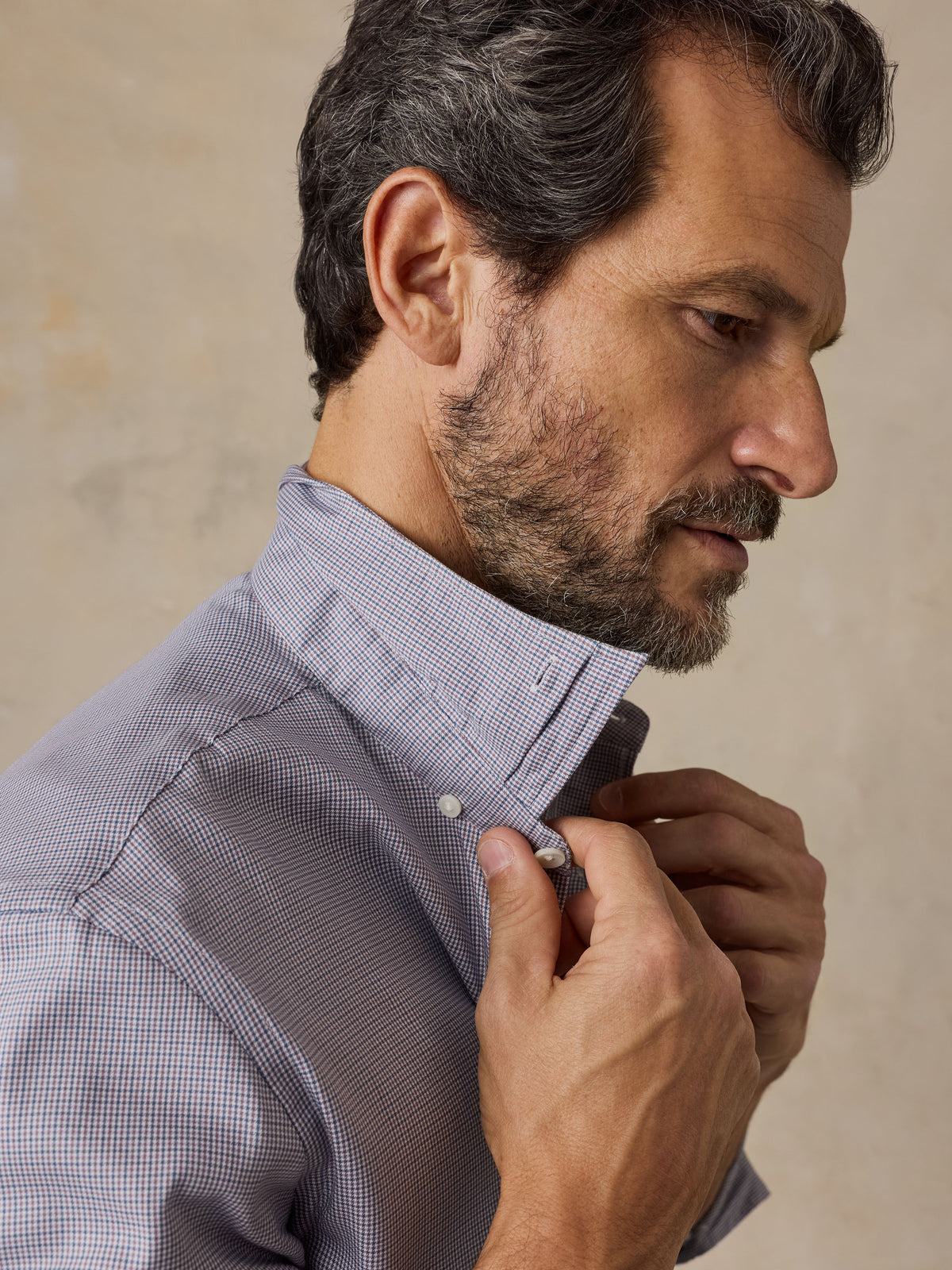 Close up profile of a man wearing a blue checkered button up shirt , image 3 of 5