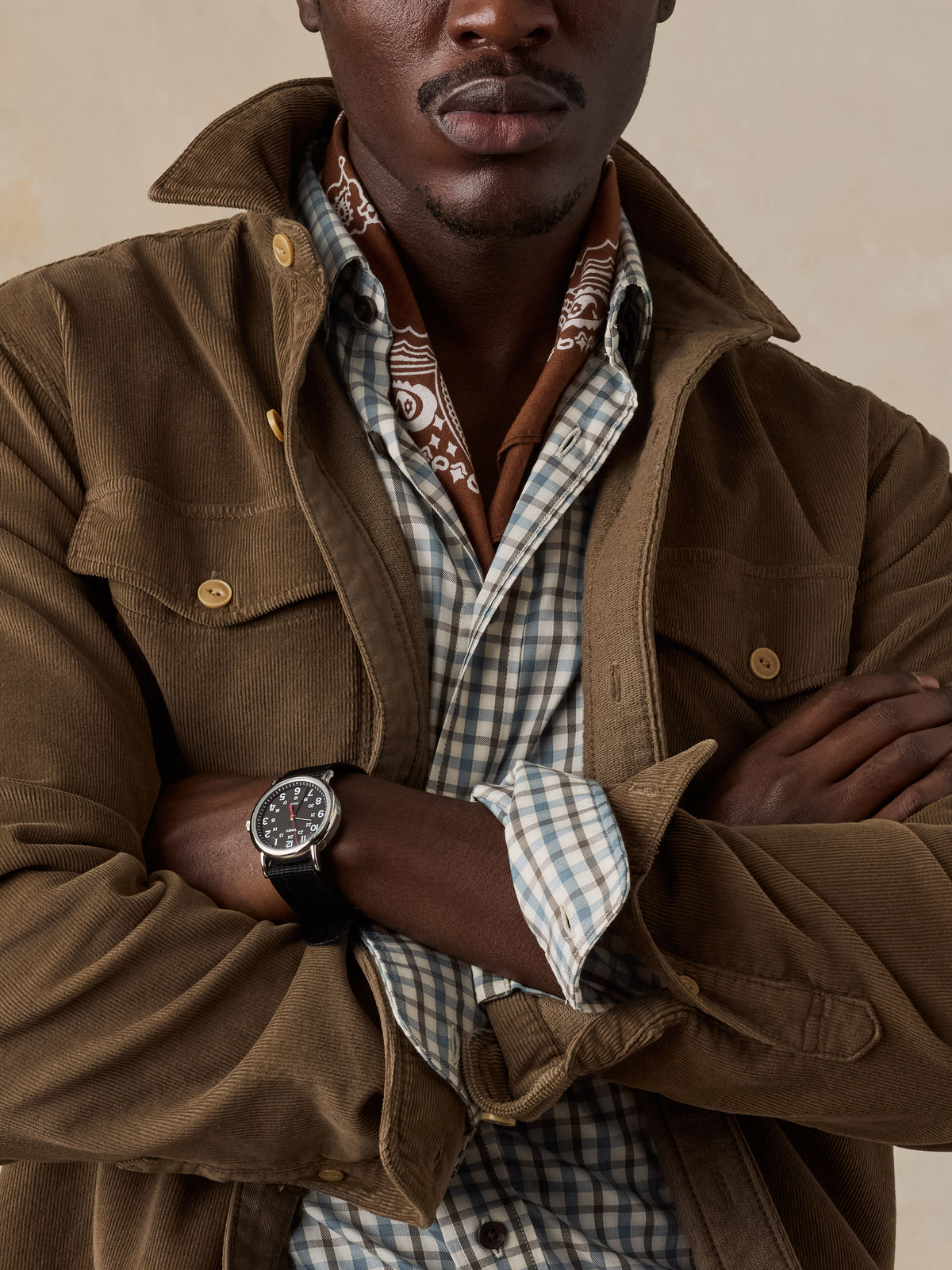 Close up of a man wearing a brown corduroy shirt over a plaid button up, image 3 of 6