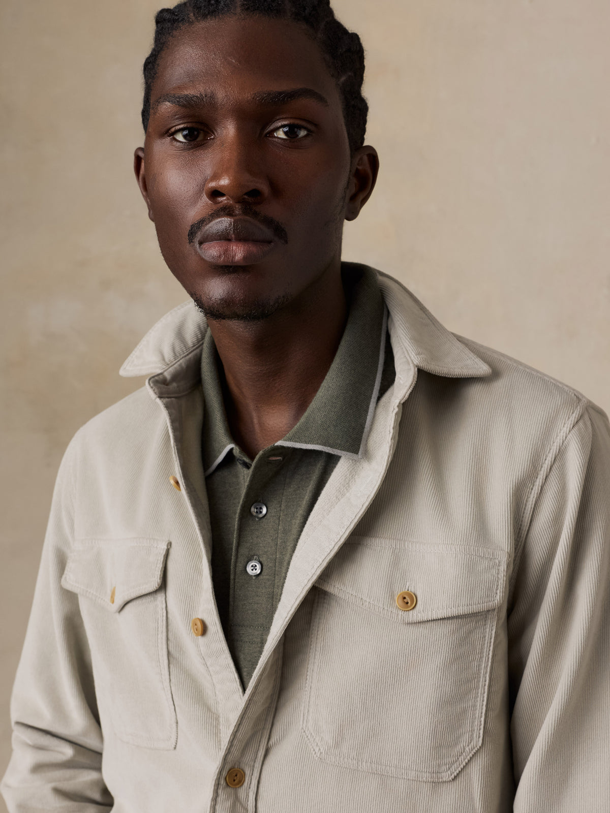 Close up of a man wearing a beige corduroy shirt over a green polo, image 4 of 6