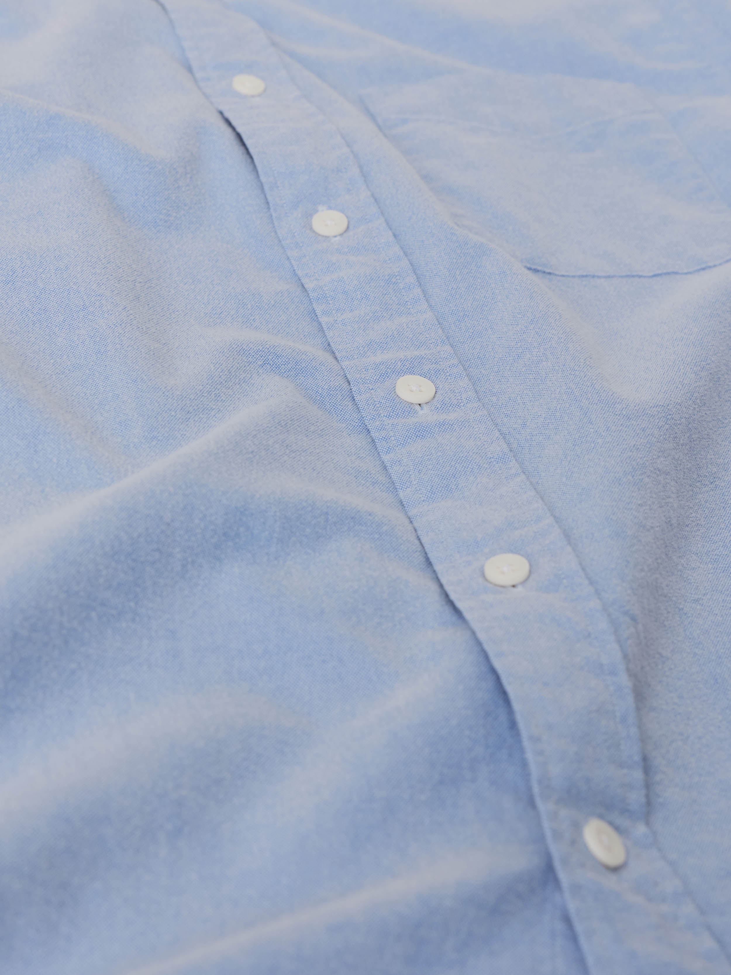 Close-up of a light blue button down shirt with white buttons, image 8 of 9