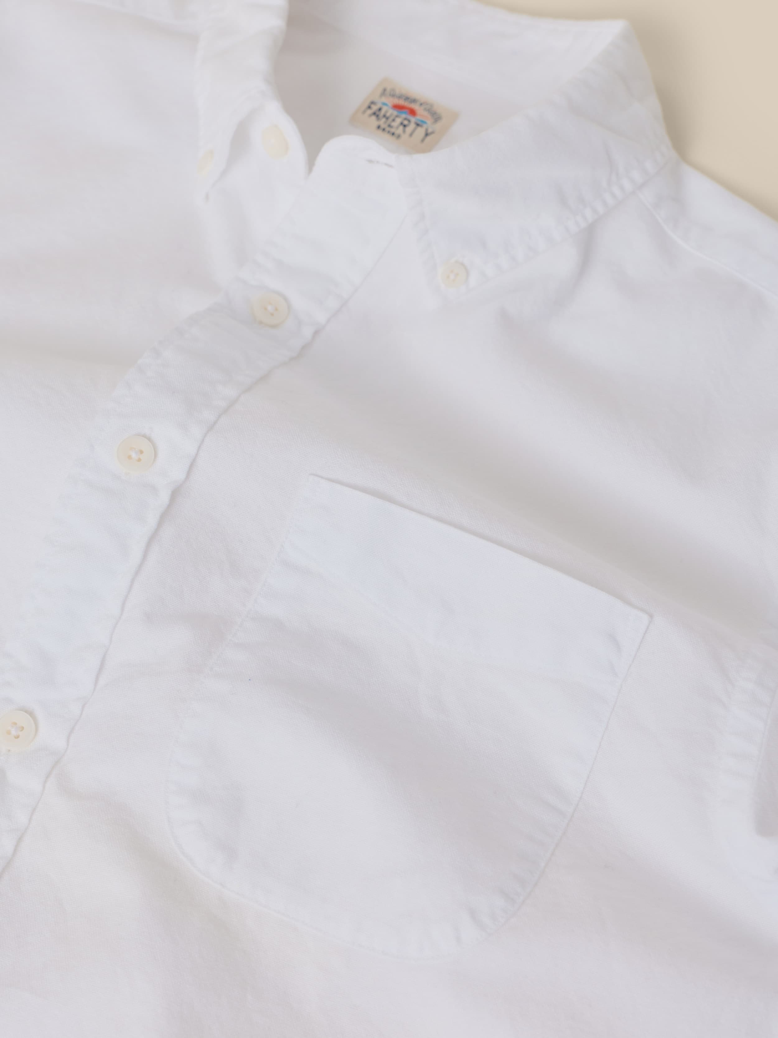 Close-up of a white shirt with a collar and button details on a light background