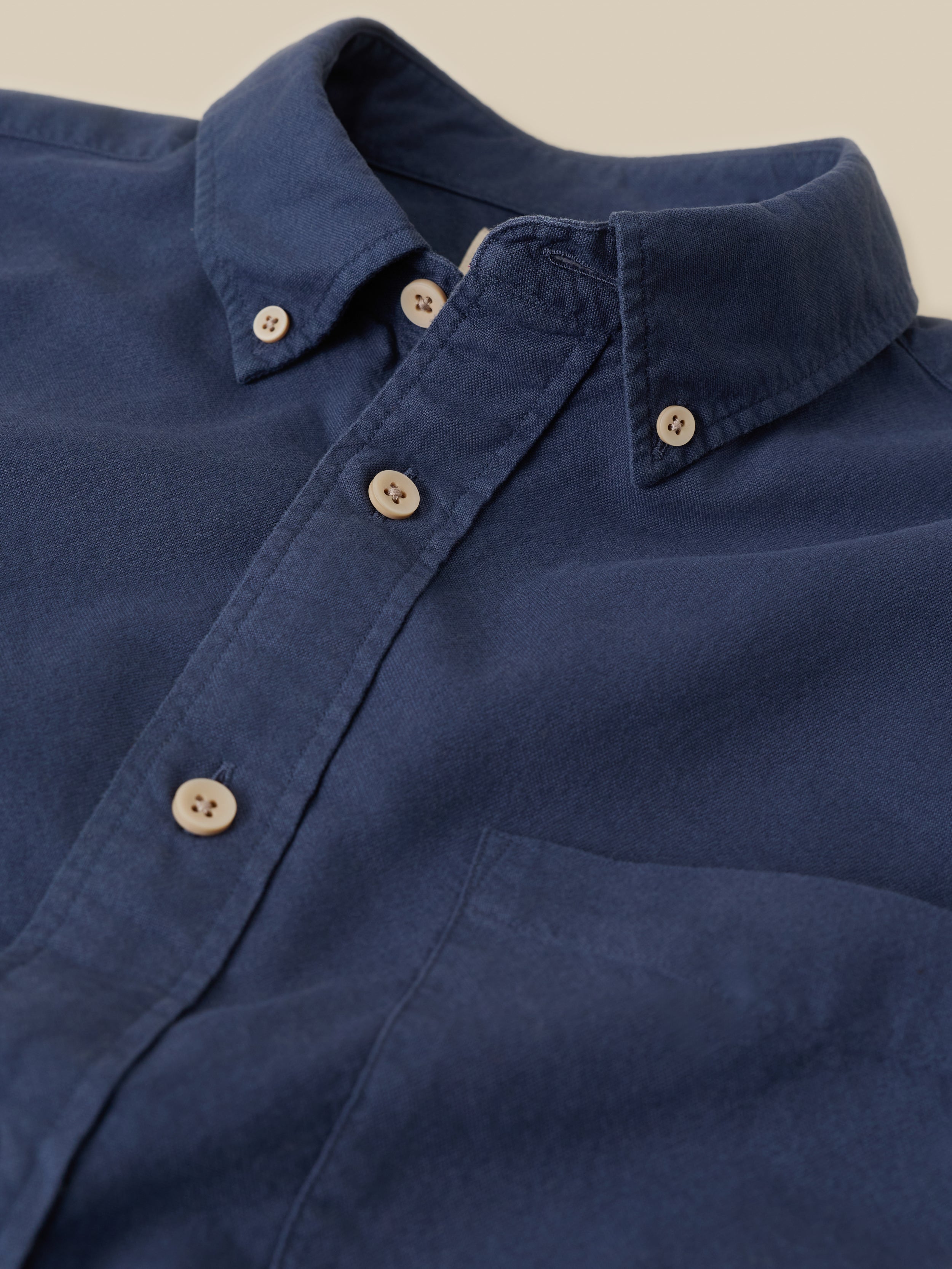 Close-up of a blue shirt with buttons on a beige background