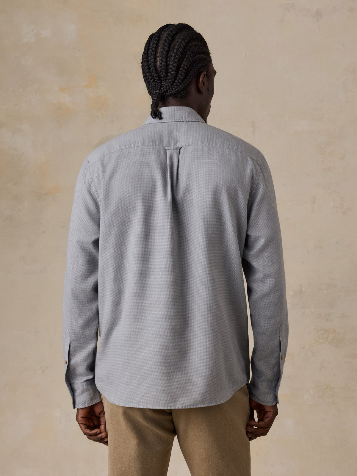 A man viewed from behind wearing a grey shirt and beige pants, image 4 of 5