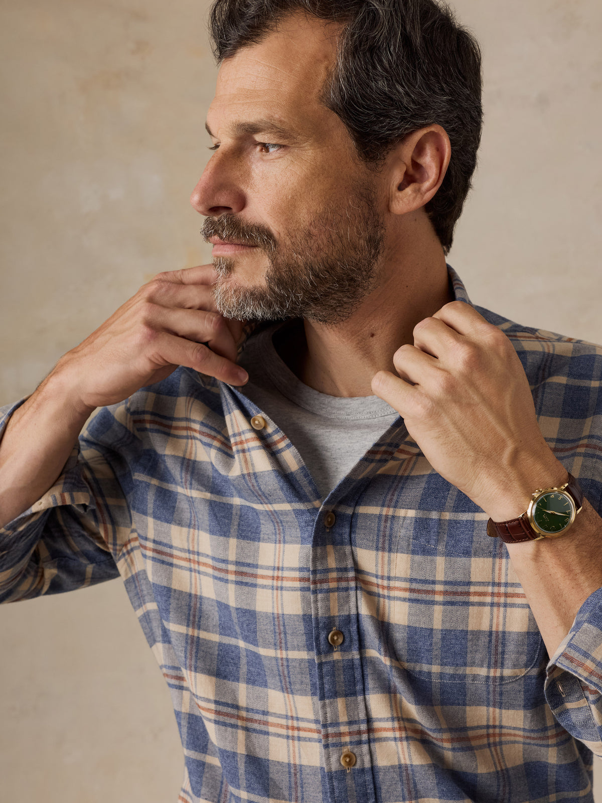 Close up of a man wearing a blue and beige plaid shirt, image 3 of 5