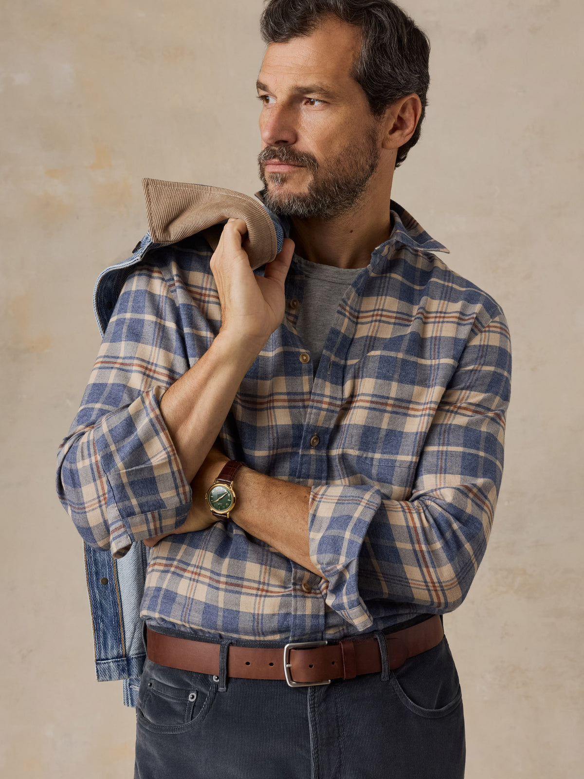 A close up of a man wearing a blue and beige plaid shirt and dark pants, image 4 of 5