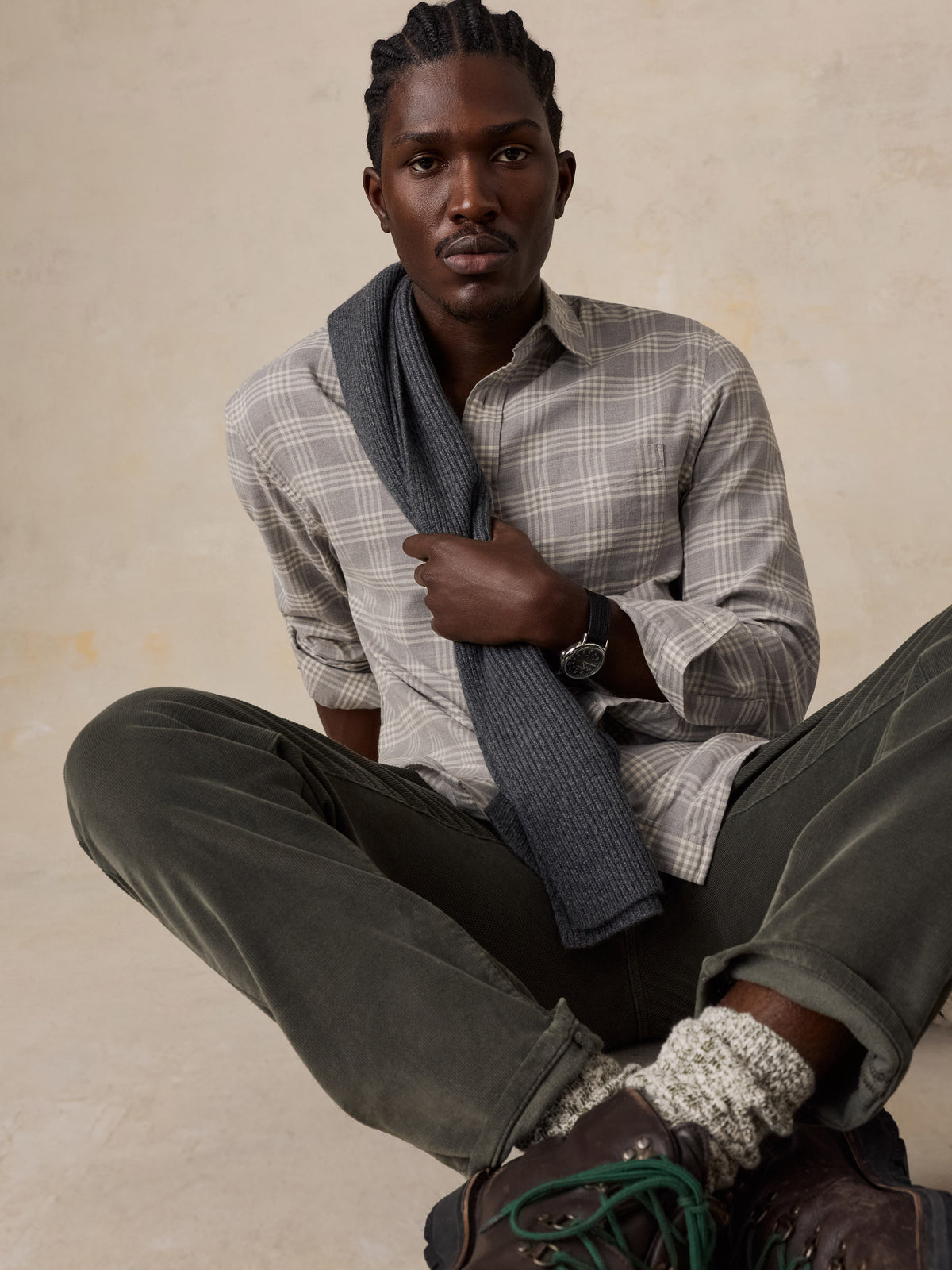 A man wearing a grey plaid button up shirt and green corduroy pants, image 2 of 5