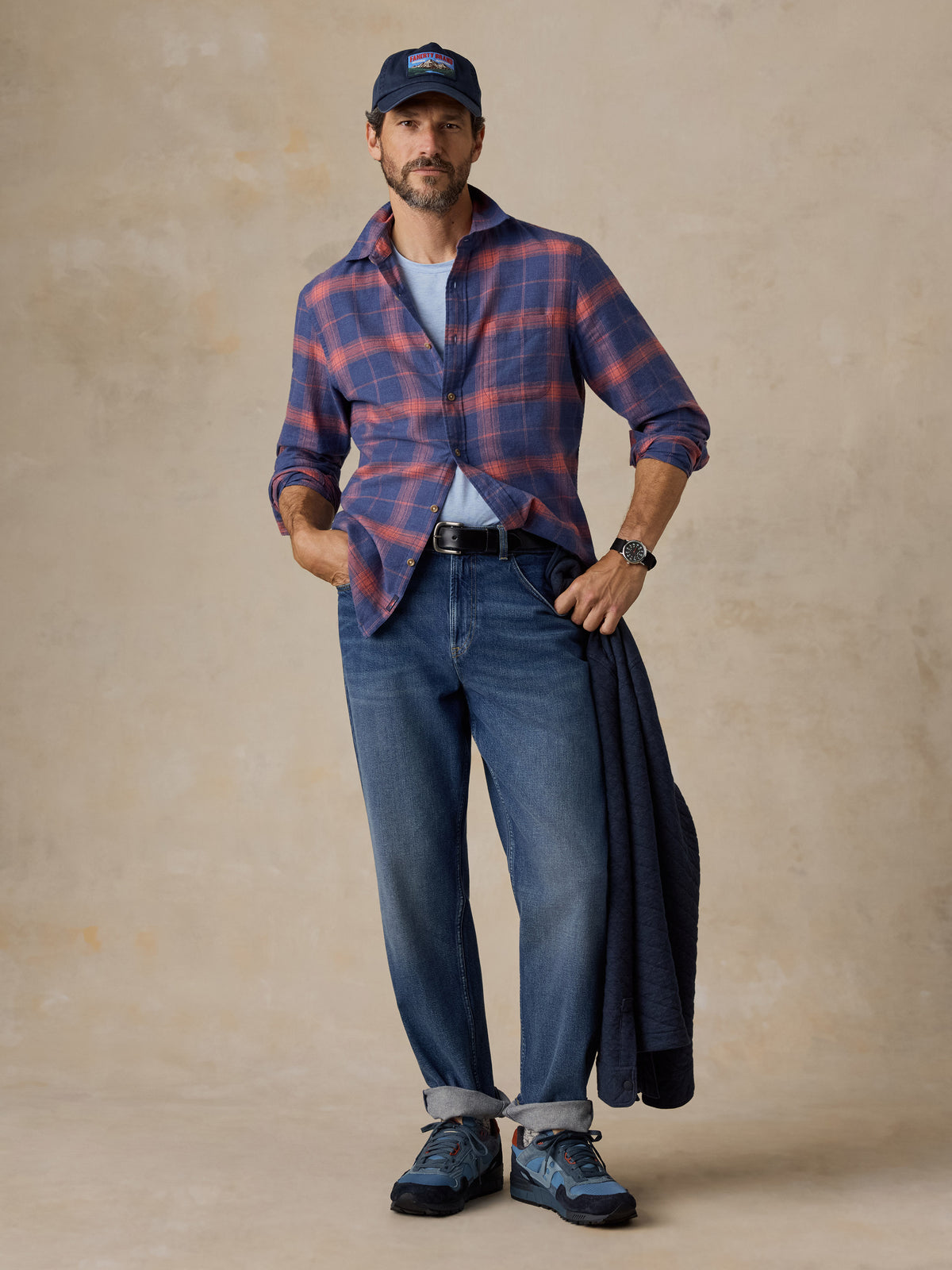 A man wearing a blue plaid shirt, blue jeans, and a hat, image 5 of 5