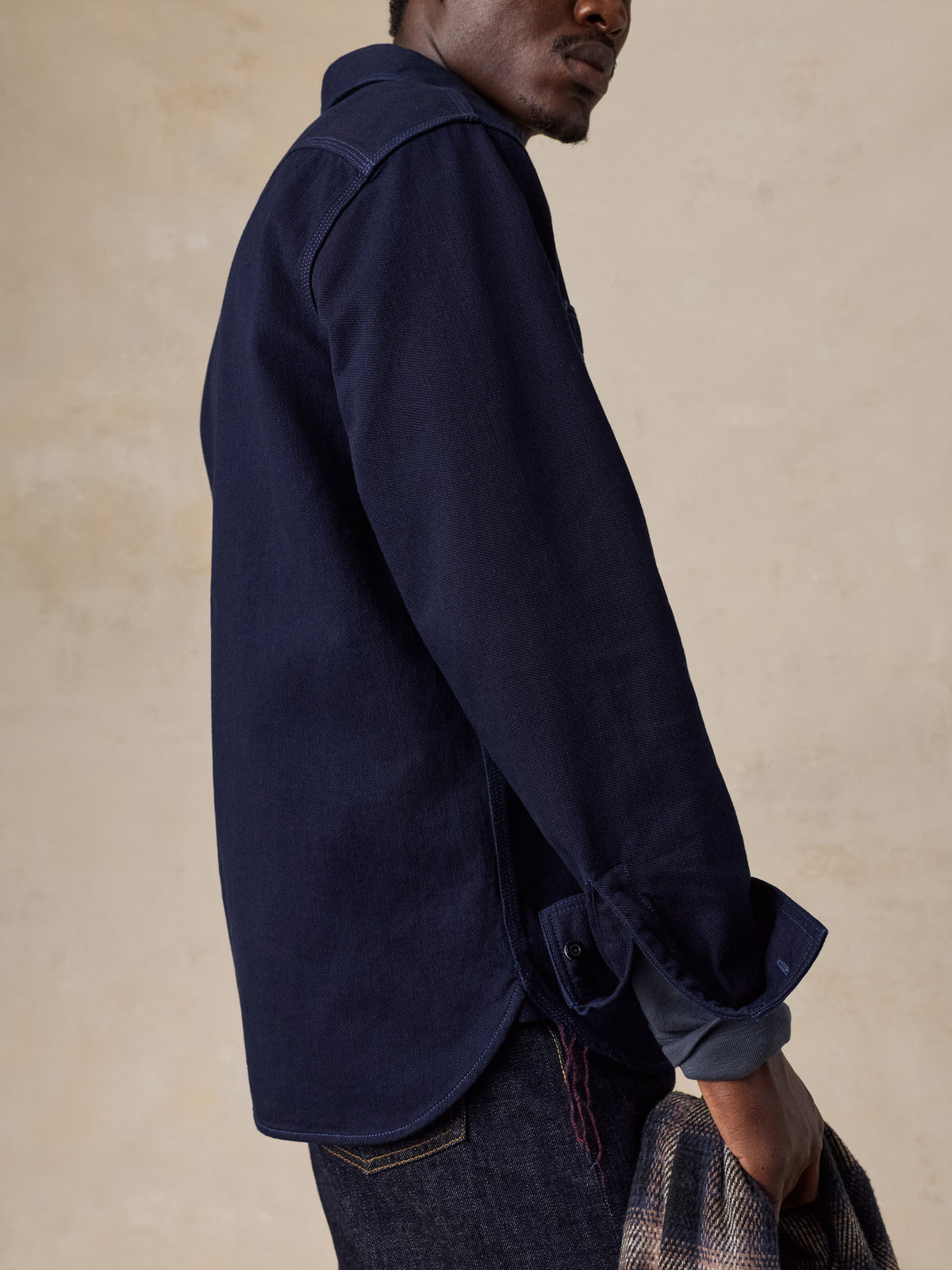 A man wearing a blue workshirt over a blue tee and blue jeans, image 6 of 6