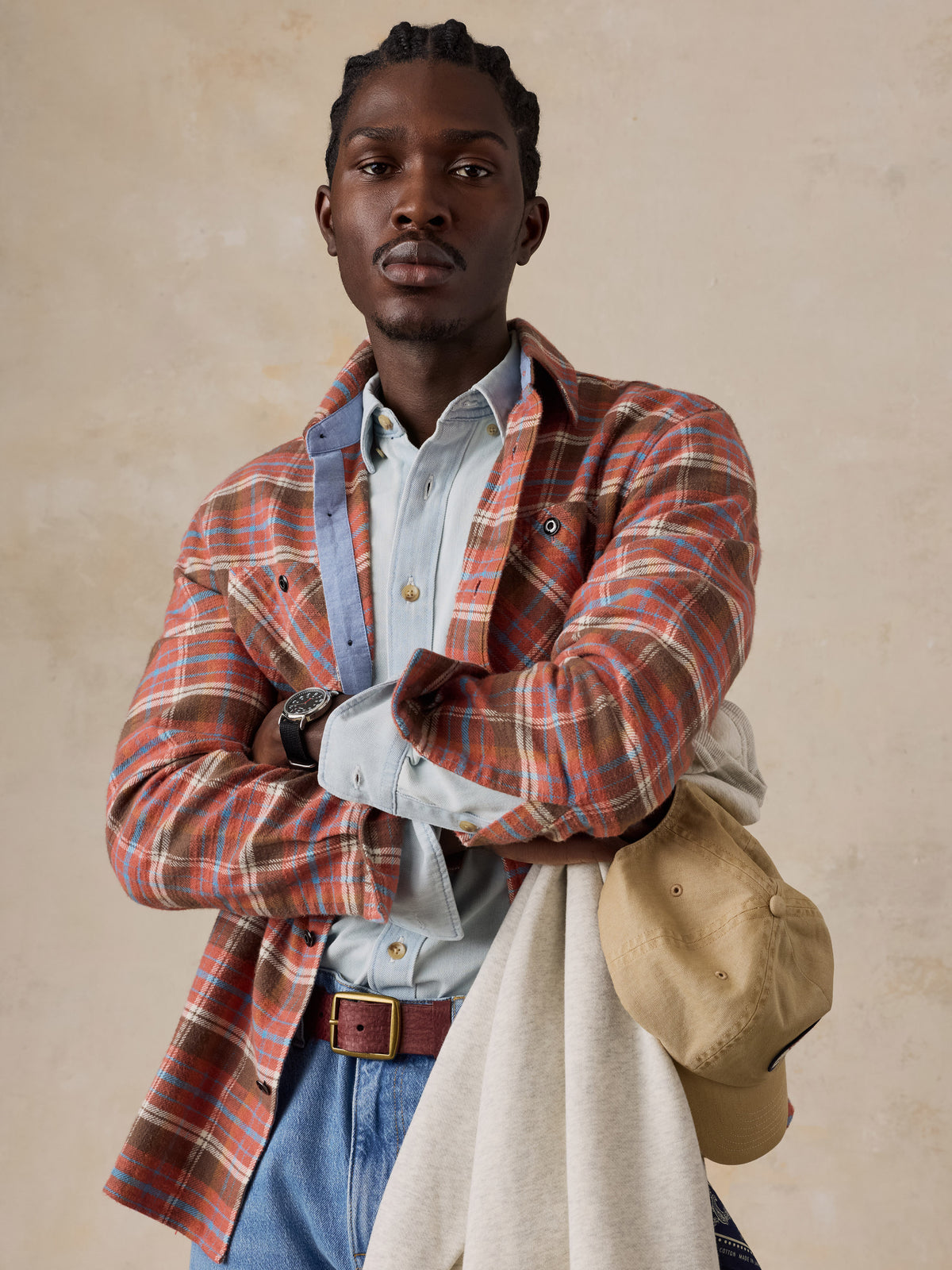 A man wearing a red plaid flannel over a chambray shirt and blue jeans, image 4 of 5
