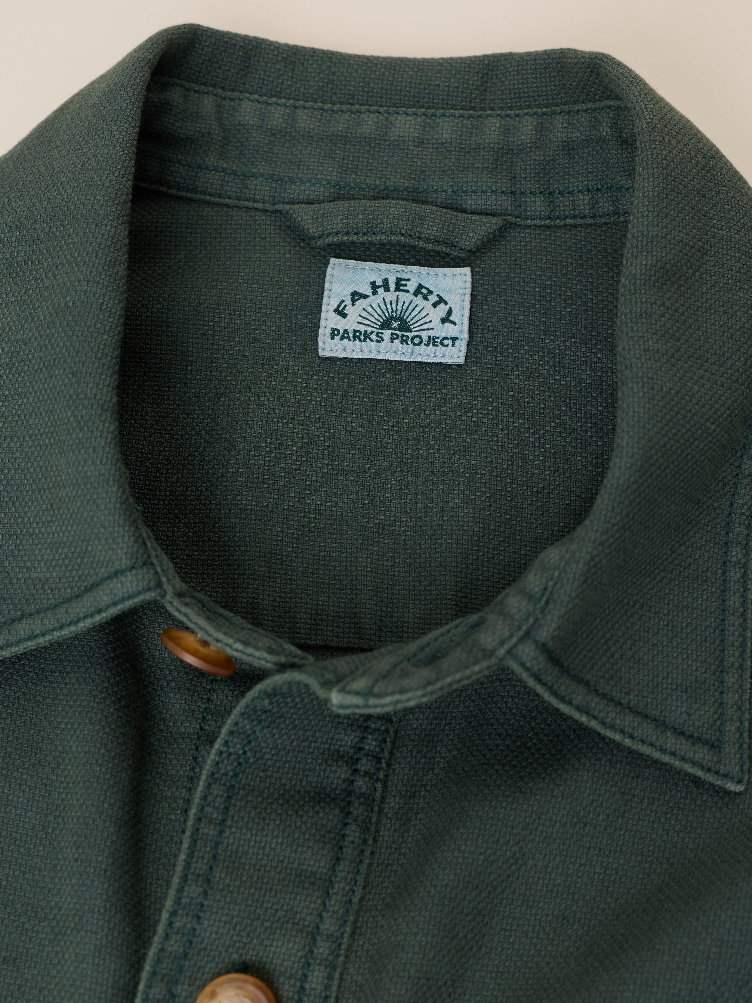 Close-up of a dark forest green textured button-up shirt collar with a visible 'Faherty Parks Project' brand label.