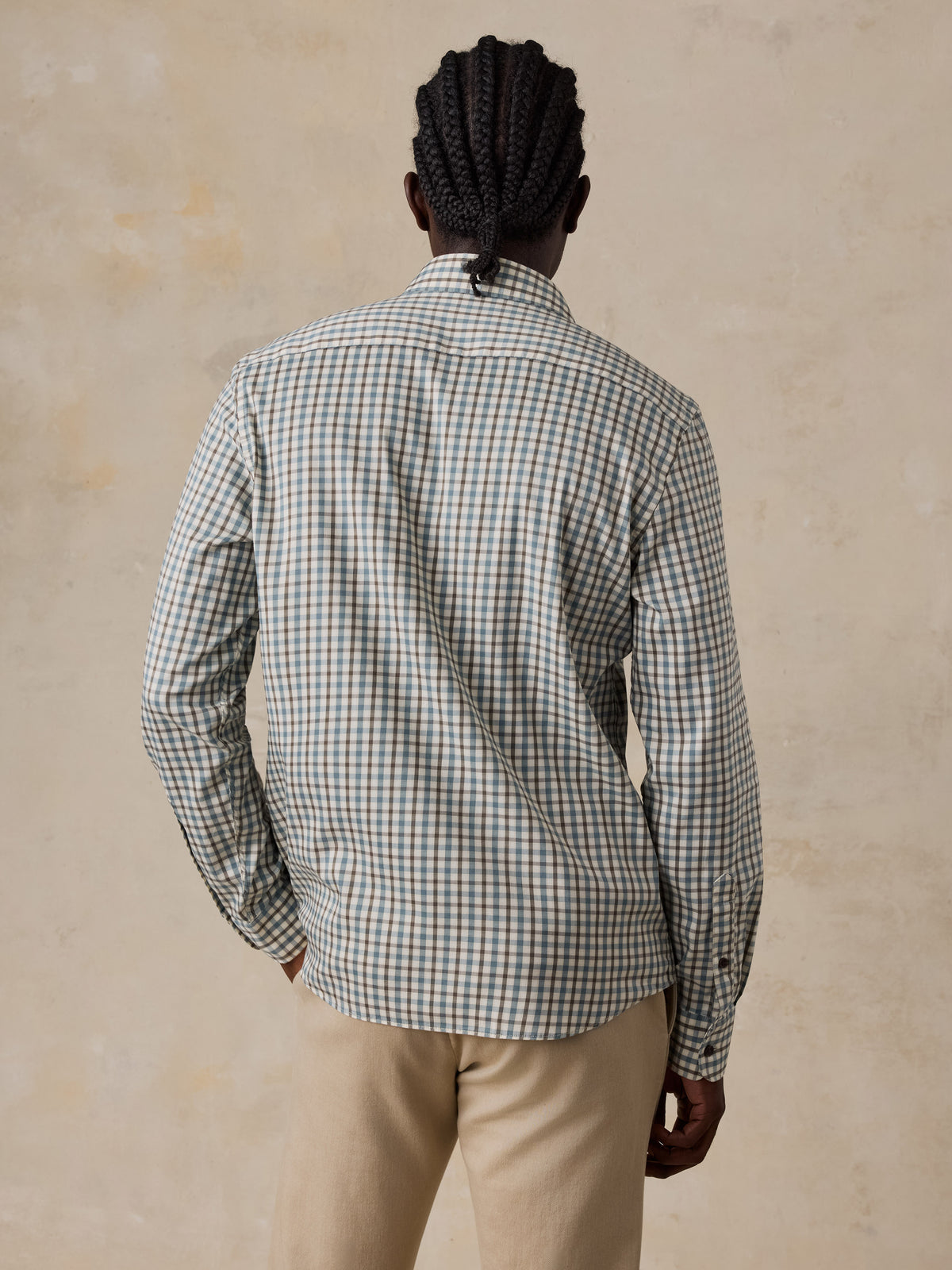 A man viewed from the back wearing a plaid shirt and beige pants, image 5 of 5