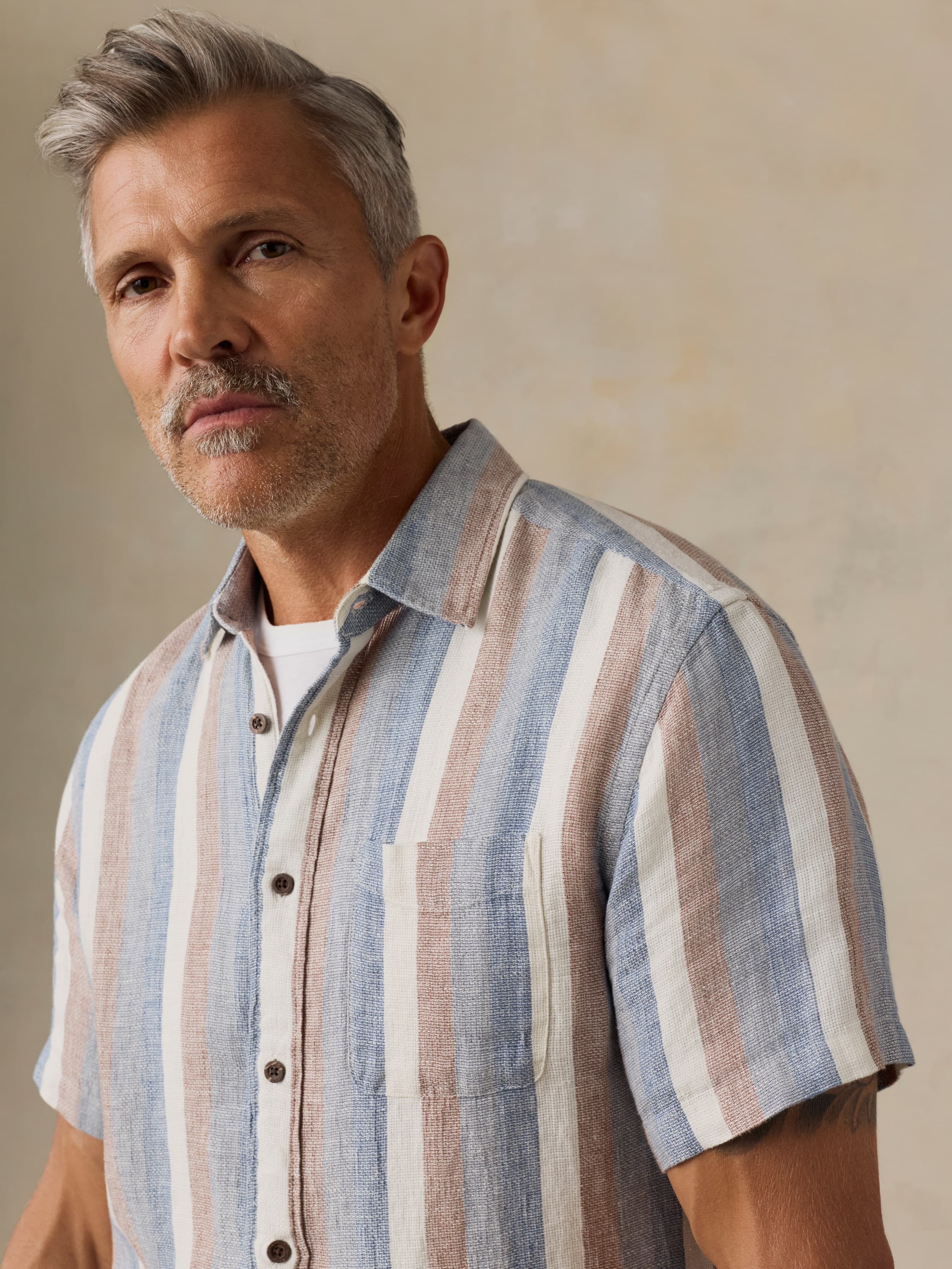 Man wearing a striped shirt against a beige background