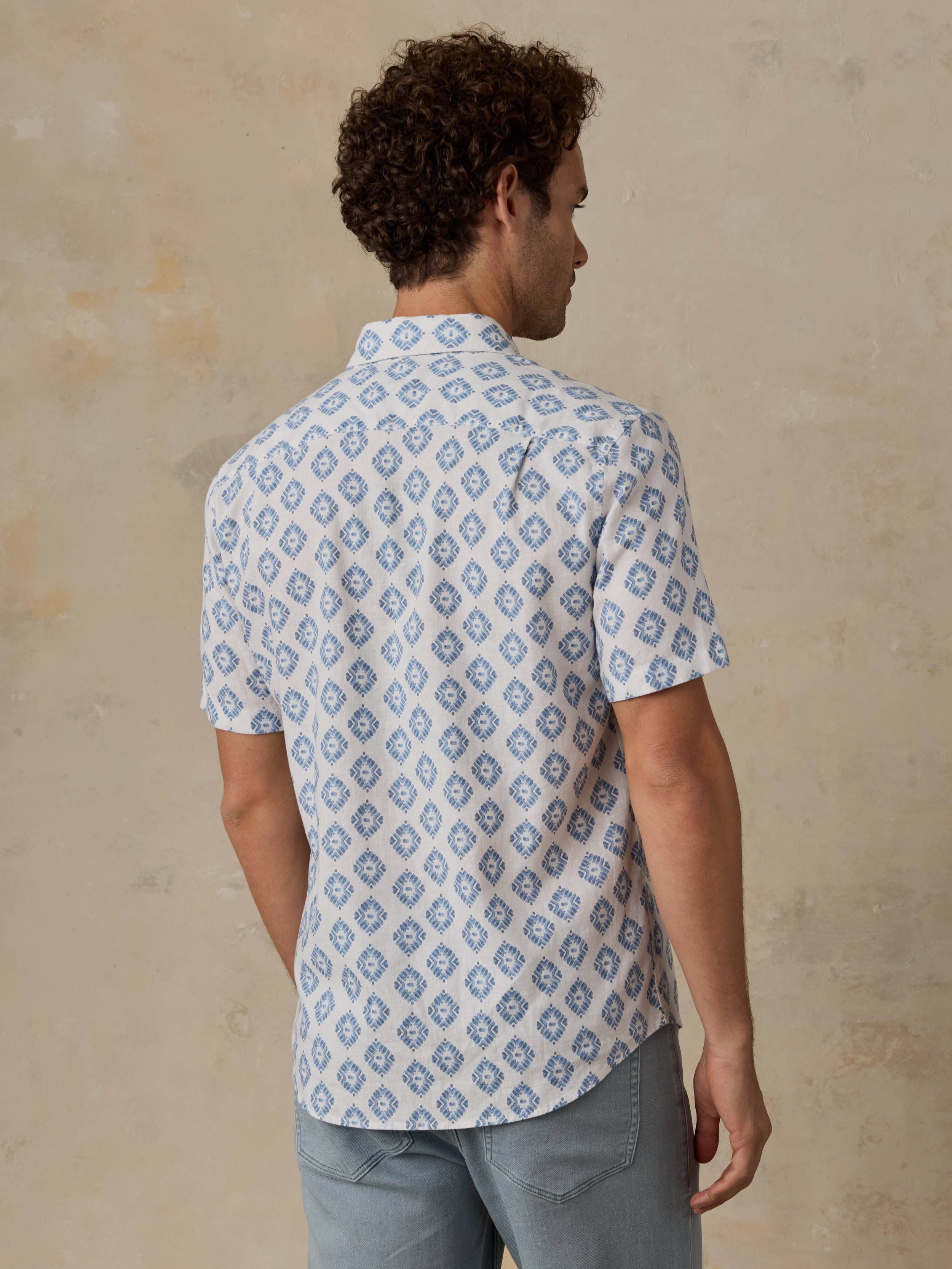 Man wearing a patterned blue and white shirt against a beige background